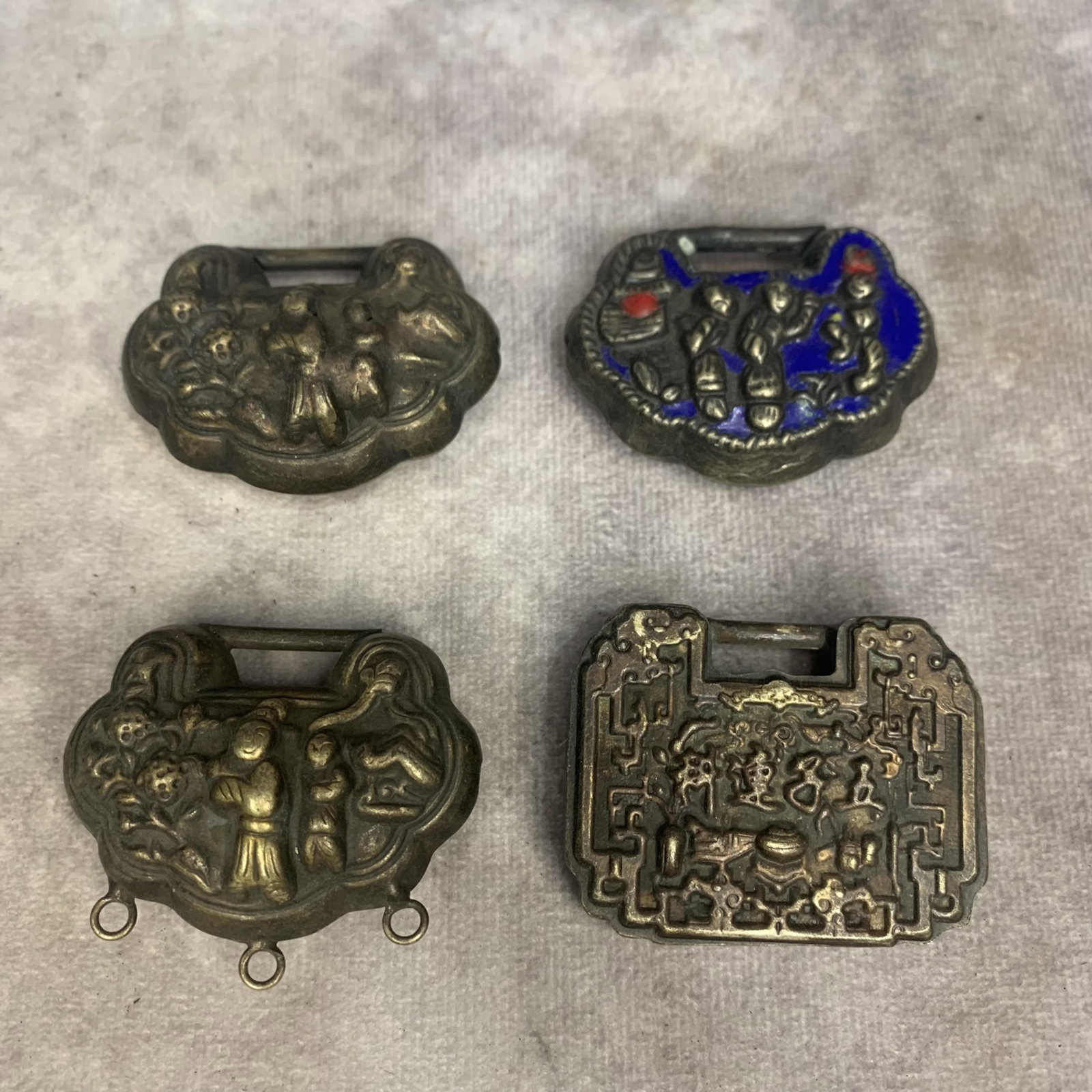 GROUP OF FOUR CARVED WHITE BRONZE SMALL LOCK PENDANT: High: 1.7 inch; Width: 2.0 inch. High: 1.5 inch; Width: 1.9 inch. High: 1.6 inch; Width: 1.9 inch. High: 1.5 inch; Width: 1.9 inch.