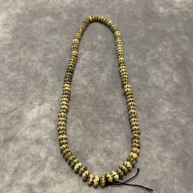 A FINELY CARVED COW BONE MADE NECKLACE