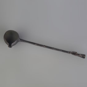 A LONG BRONZE MEASURING SPOON