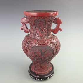 CARVED RED LACQUER VASE WITH FRAMED FLORAL DESIGN AND BEAST-SHAPED HANDLES