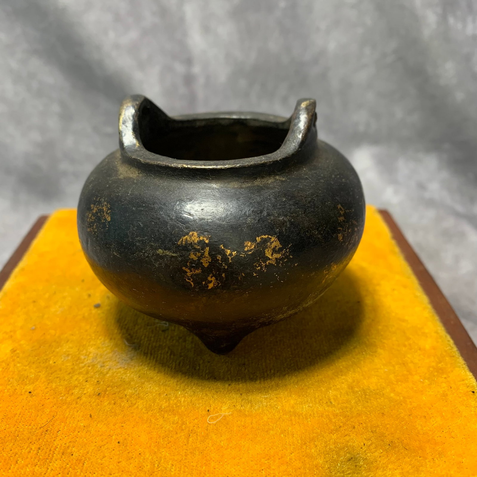 A GILT-BRONZE TRIPOD CENSER WITH ‘FO’ MARK AND ARCHED HANDLES: Qing Dynasty; High: 2.6 inch; Diameter: 3.2 inch