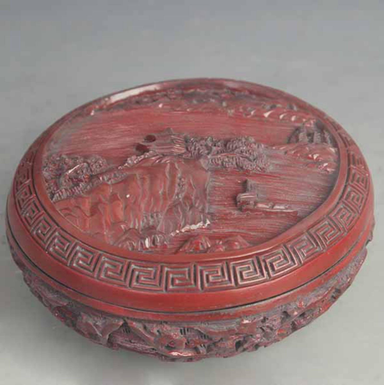 A CARVED RED LACQUER ‘LANDSCAPE’ INCENSE BOX: Qing Dynasty; High: 2.75 inch; Diameter: 5.75 inch;