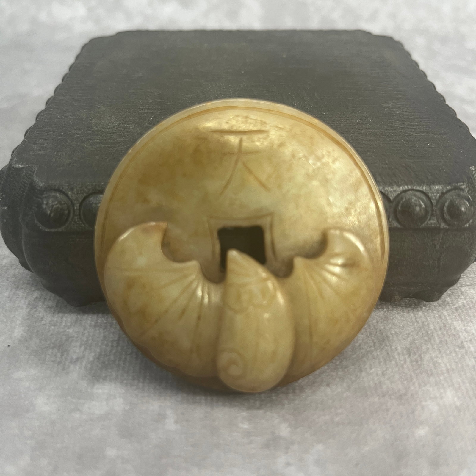 A FINE HETIAN CELADON JADE IN FIGURE OF COIN WITH BAT: Qing Dynasty; High: 0.48 inch; Diameter: 2.14 inch;