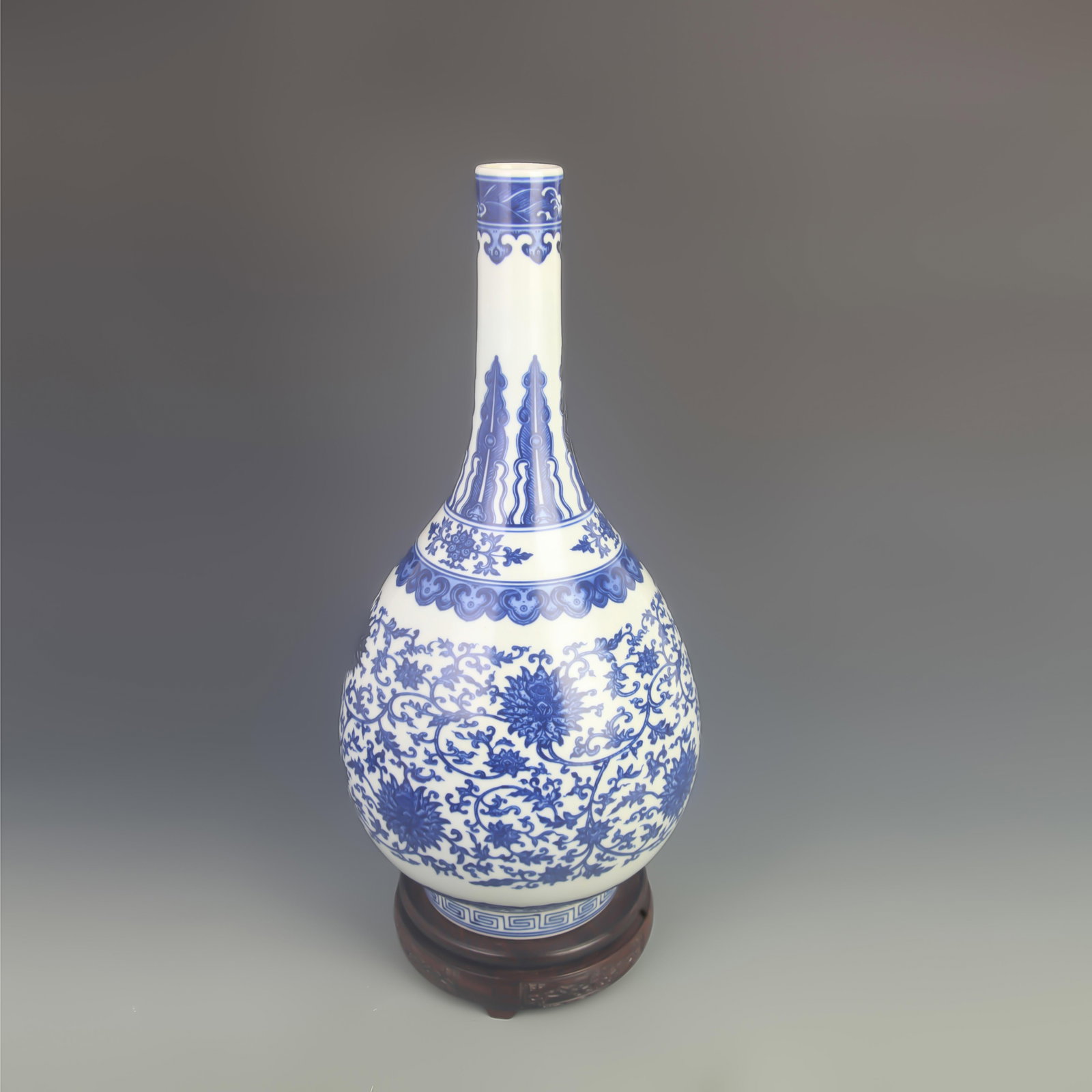 A BLUE AND WHITE LOTUS SCROLL LONG-NECK VASE: Qing Dynasty; High: 17.0 inch; Diameter: 8.00 inch; Woodbase for picture and display only