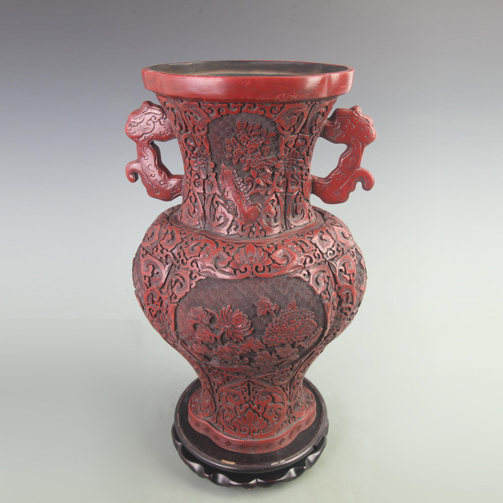 A CARVED CINNABAR LACQUER VASE WITH FLORAL PANELS AND BEAST-HEAD HANDLES: Qing Dynasty; High: 17.8 inch; Width: 7.5 inch; Long: 11 inch; Woodbase for picture and display only