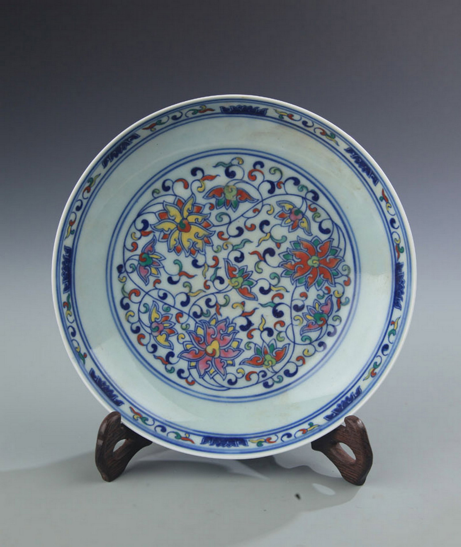 A DOUCAI COLOR LOTUS AND SCROLL PATTERN PORCELAIN PLATE: Qing Dynasty; High: 1.5 inch; Diameter: 7.75 inch; Woodbase for picture and display only