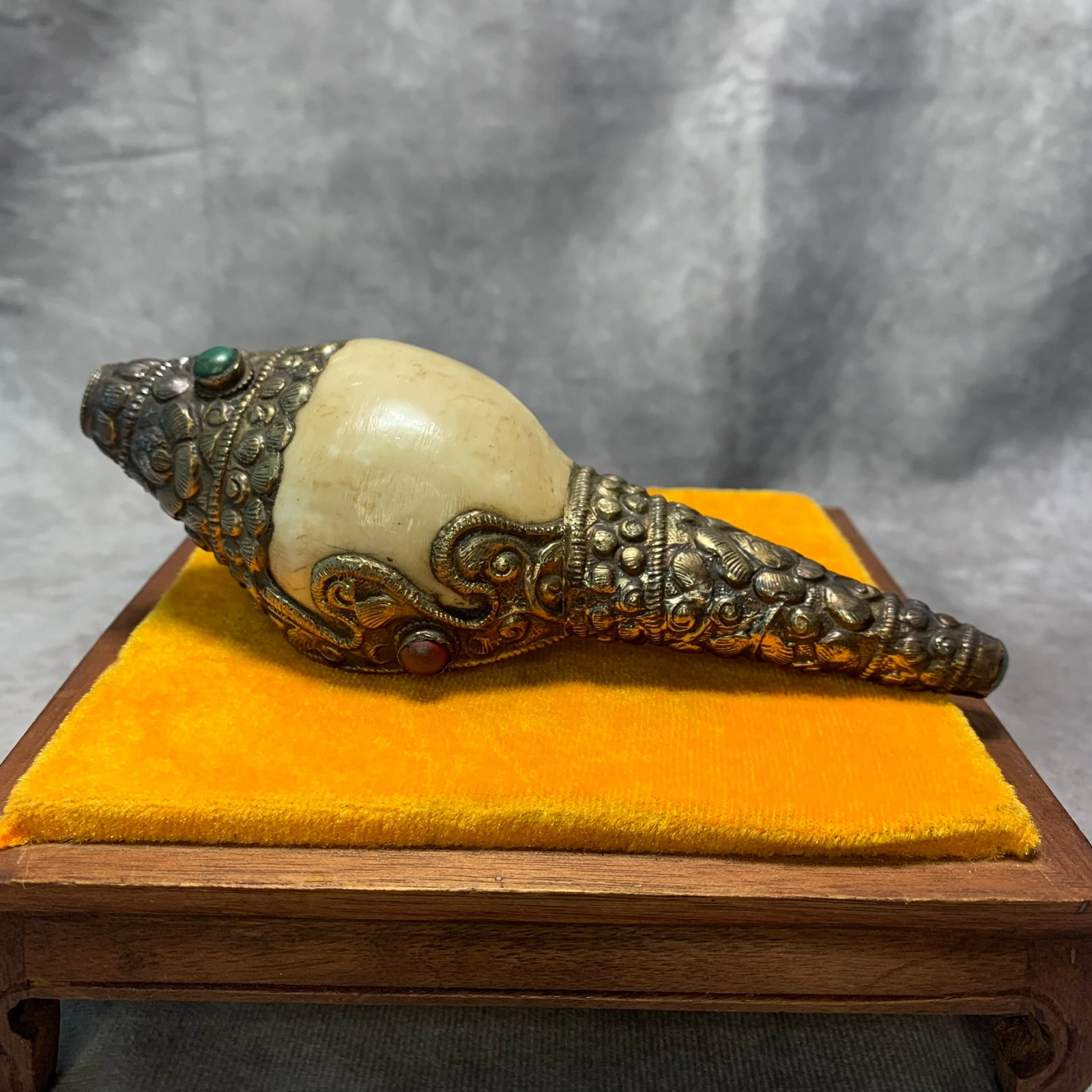 A SILVER-MOUNTED GEM-INLAID TIBETAN CONCH SHELL: Qing Dynasty; Long: 6.7 inch; Width: 2.5 inch; H; 2.1 inch; Woodbase for picture and display only