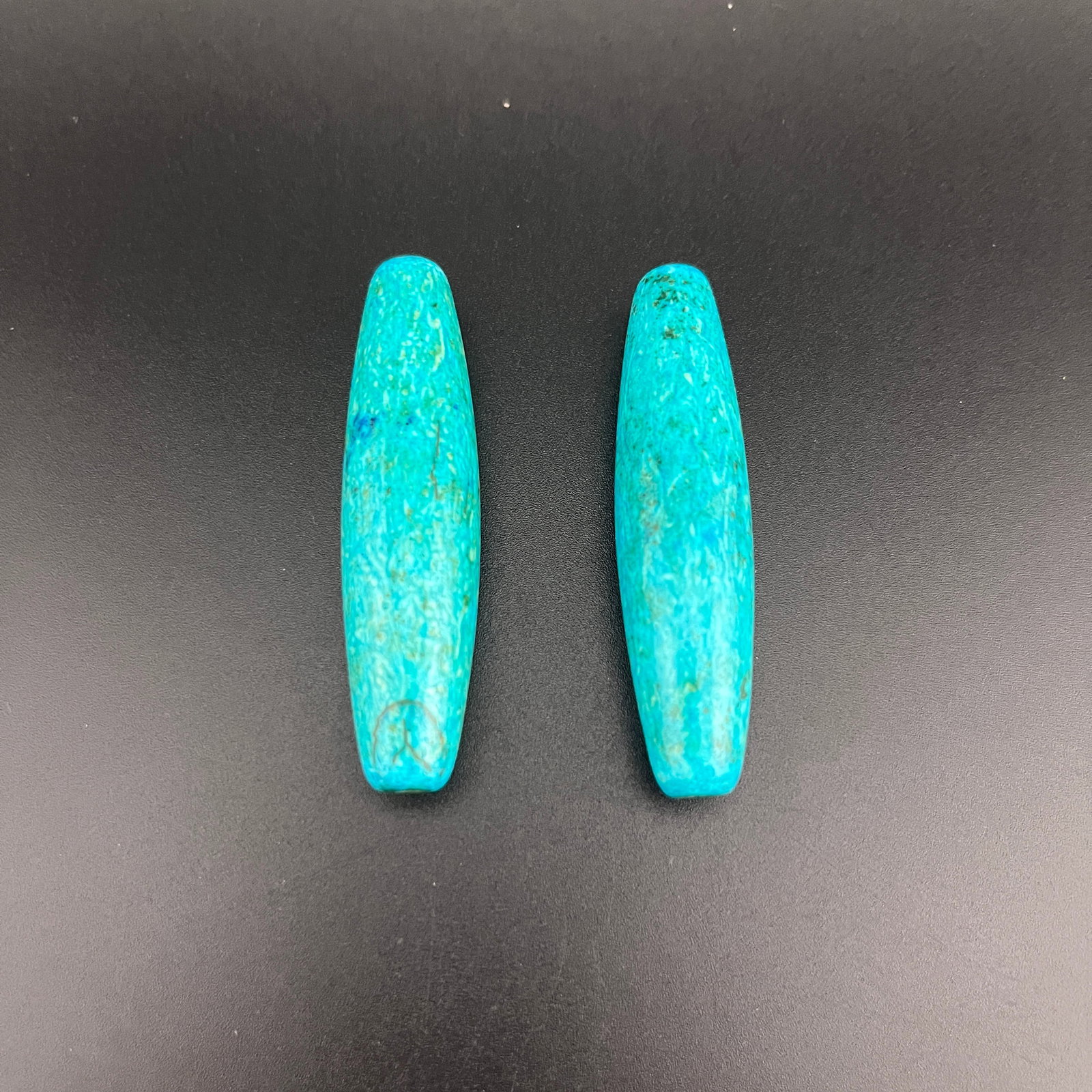 PAIR OF TUBULAR TURQUOISE BEADS: Modern; Long: 2.4 inch; Diameter: 0.6 inch; Woodbase for picture and display only