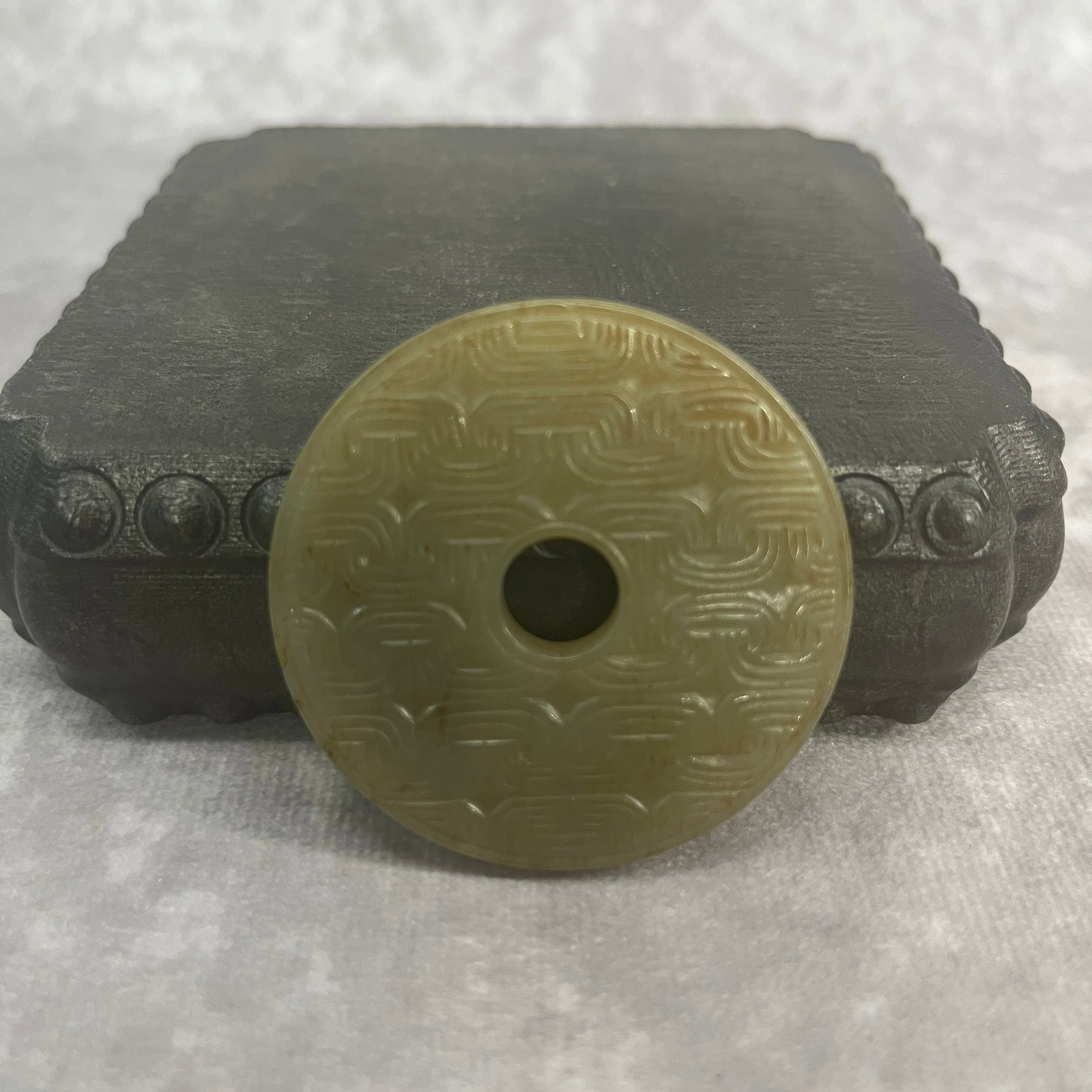 A FINE CLOUD PATTERN JADE BI DISC: Qing Dynasty; High: 0.19 inch; Diameter: 1.98 inch; Woodbase for picture and display only