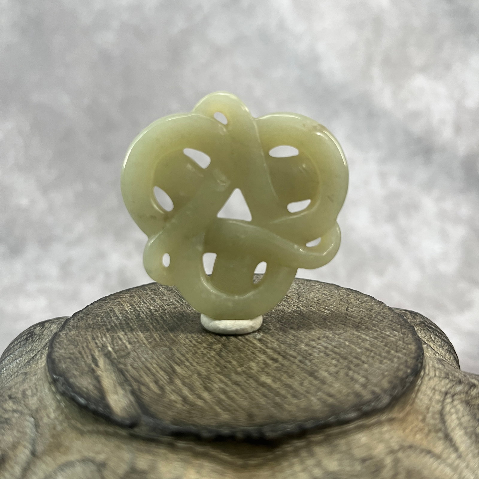 A FINE HETIAN JADE IN FIGURE OF ENDLESS KNOT: Qing Dynasty; Long: 1.78 inch; Width:1.72 inch; Heigh: 0.31 inch; Woodbase for picture and display only
