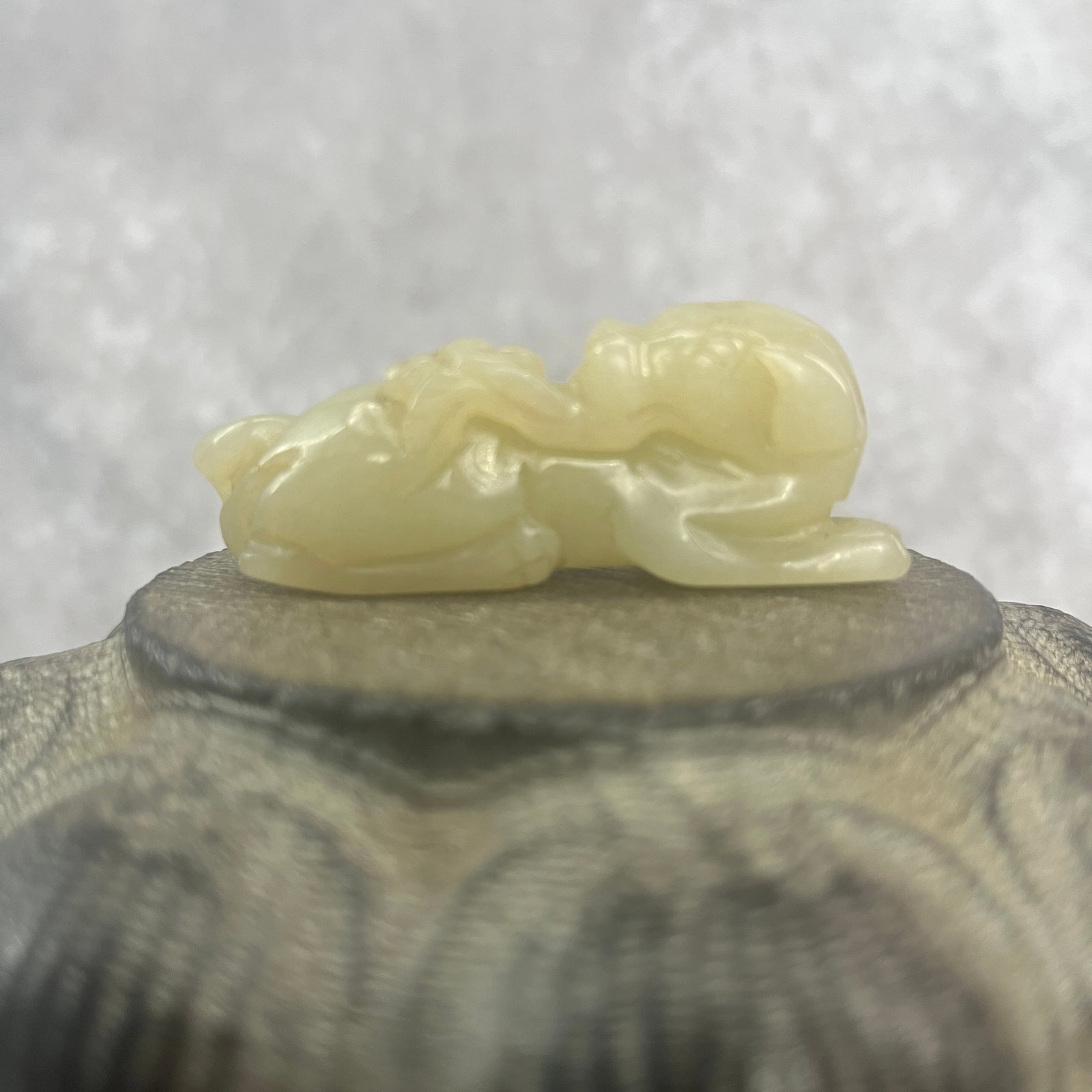 A FINE HETIAN CELADON JADE IN FIGURE OF PIXU WITH RUYI: Qing Dynasty; Long: 2.4 inch; Width: 0.92 inch; High: 0.72 inch; Woodbase for picture and display only