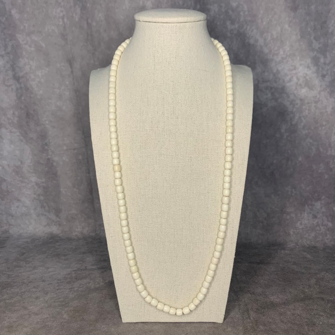A FINE OX BONE MADE NECKLACE: Modern; Long: 15.5 inch; Each Bead Diameter: 0.3 inch; Woodbase for picture and display only