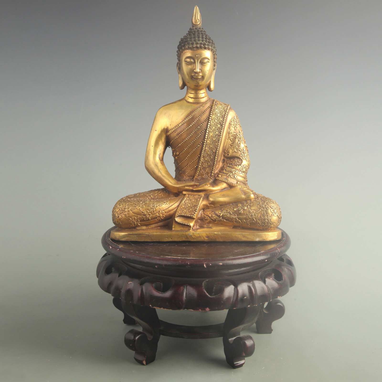 A GILT BRONZE SHAKYAMUNI BUDDHA: 20th Century; High: 10.5 inch; Width: 7.70 inch; Woodbase for picture and display only