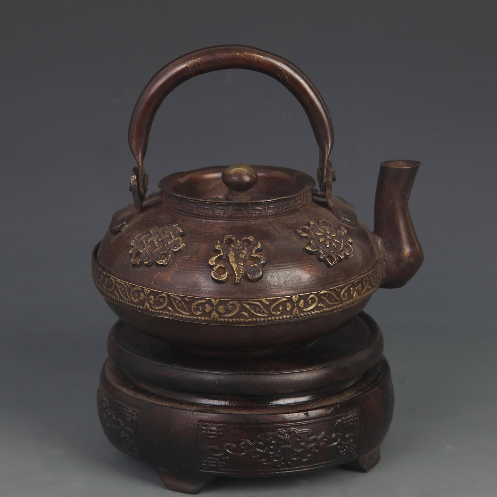 A TIBETAN-STYLE COPPER EWER WITH REPOUSSE EIGHT AUSPICIOUS SYMBOLS: 20th Century; High: 4.75 inch; Diameter: 2.25 inch; Long: 5.00 inch; Woodbase for picture and display only