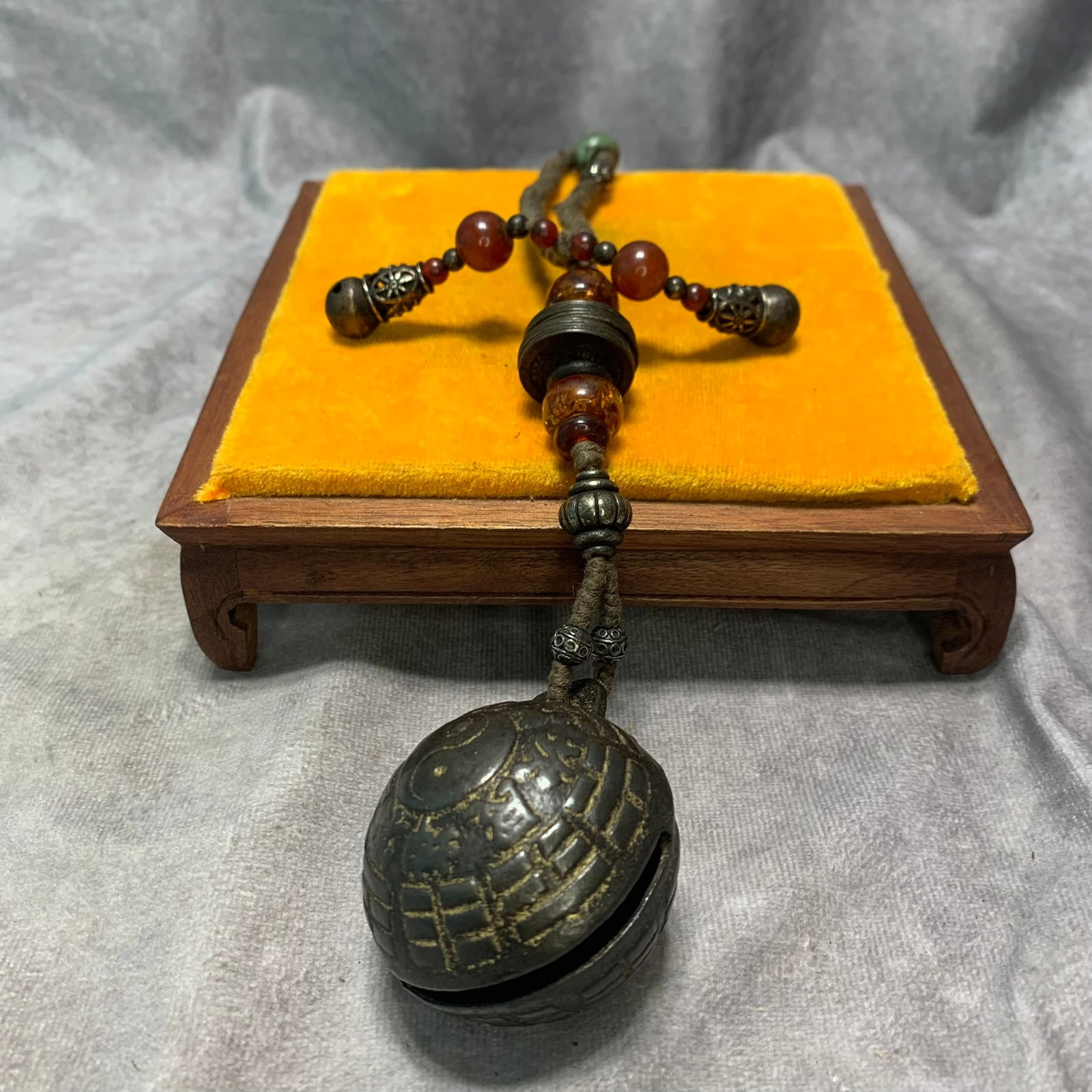 A COPPER PENDANT WITH AMBER AND COIN CHARM BELL: Republic Period; Long: 9.5 inch; Width: 2 inch; H; 2 inch; Woodbase for picture and display only
