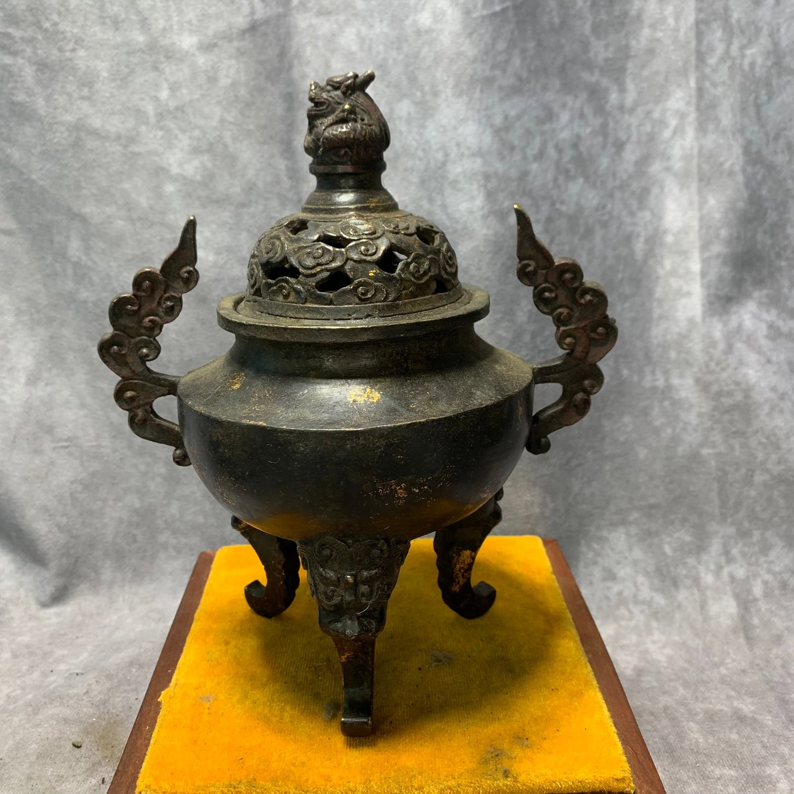 QIAN LONG MARKED GILT BRONZE TRIPOD INCENSE BURNER WITH CLOUD HANDLES AND LION FEET: Qing Dynasty; High: 7.8 inch; Diameter: 6.6 inch; Wooden base for picture and display only.