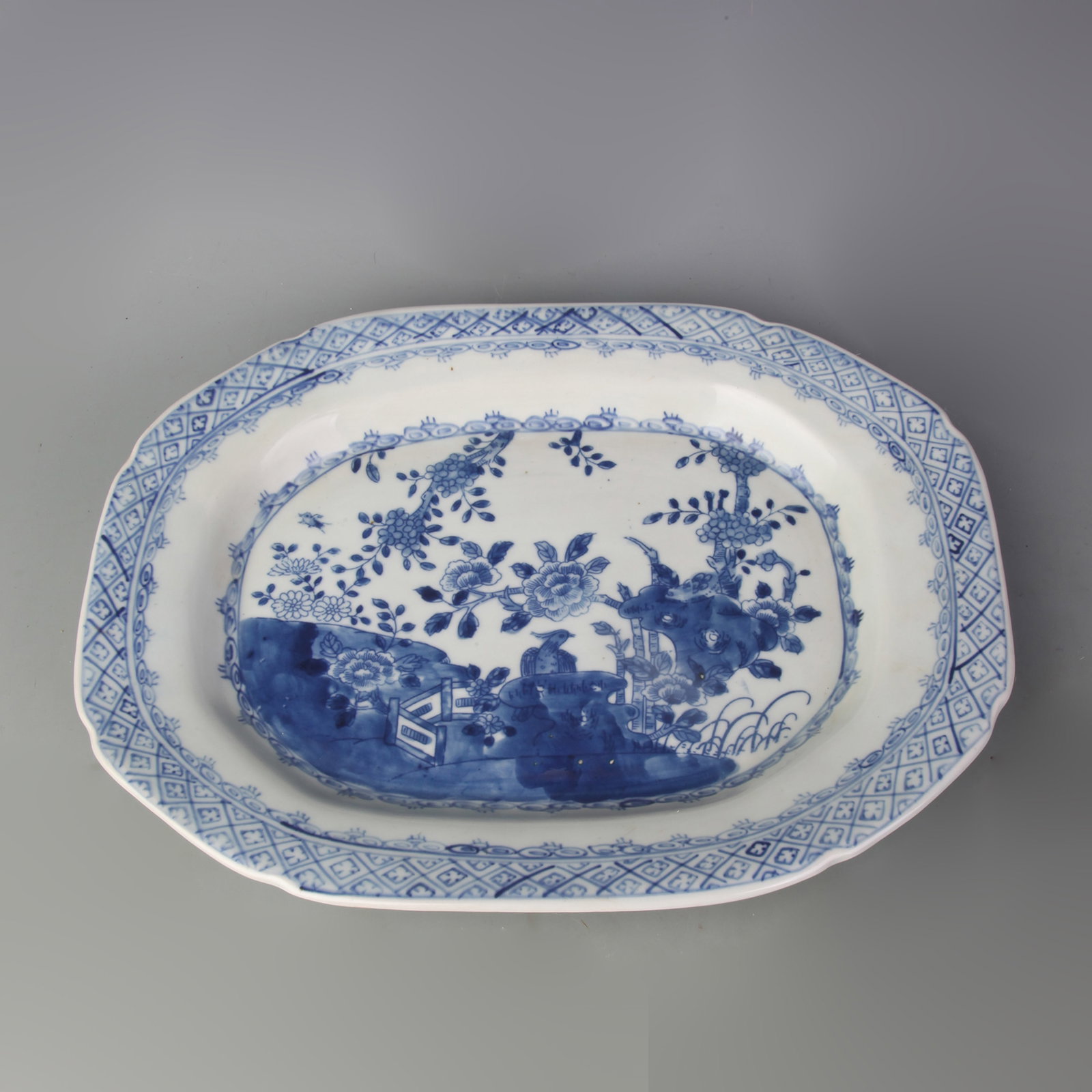 A BLUE AND WHITE PORCELAIN PLATE WITH BIRD-AND-FLOWER MOTIF: Qing Dynasty; Long: 13.9 inch; Wooden base for picture and display only.