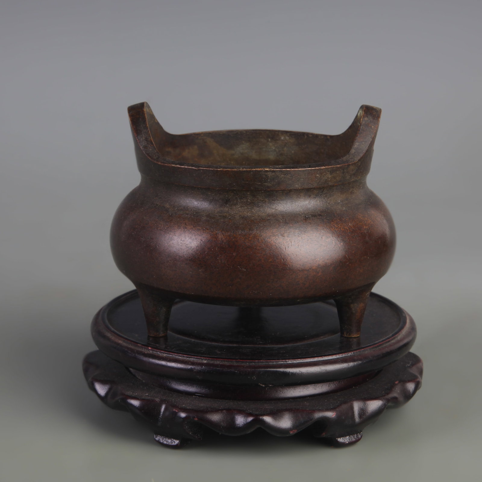 A BRONZE TRIPOD CENSER WITH BRIDGE HANDLES: Qing Dynasty; Diameter: 4.0 inch; High: 3.2 inch; Wooden base for picture and display only.