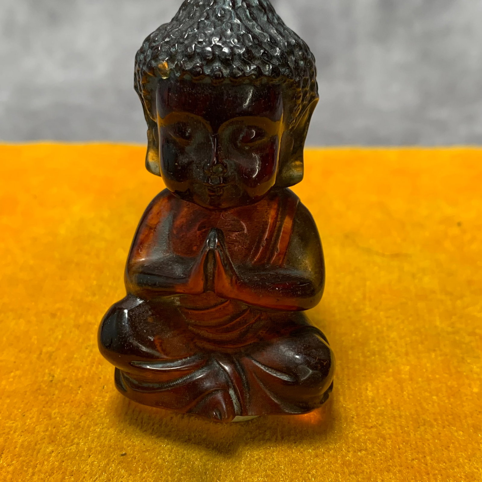 A REPUBLIC PERIOD AMBER CARVING OF A BABY BUDDHA: Republic Period: Long: 1.4 inch; Width: 1 inch; High: 2.4 inch. Wooden base for picture and display only.