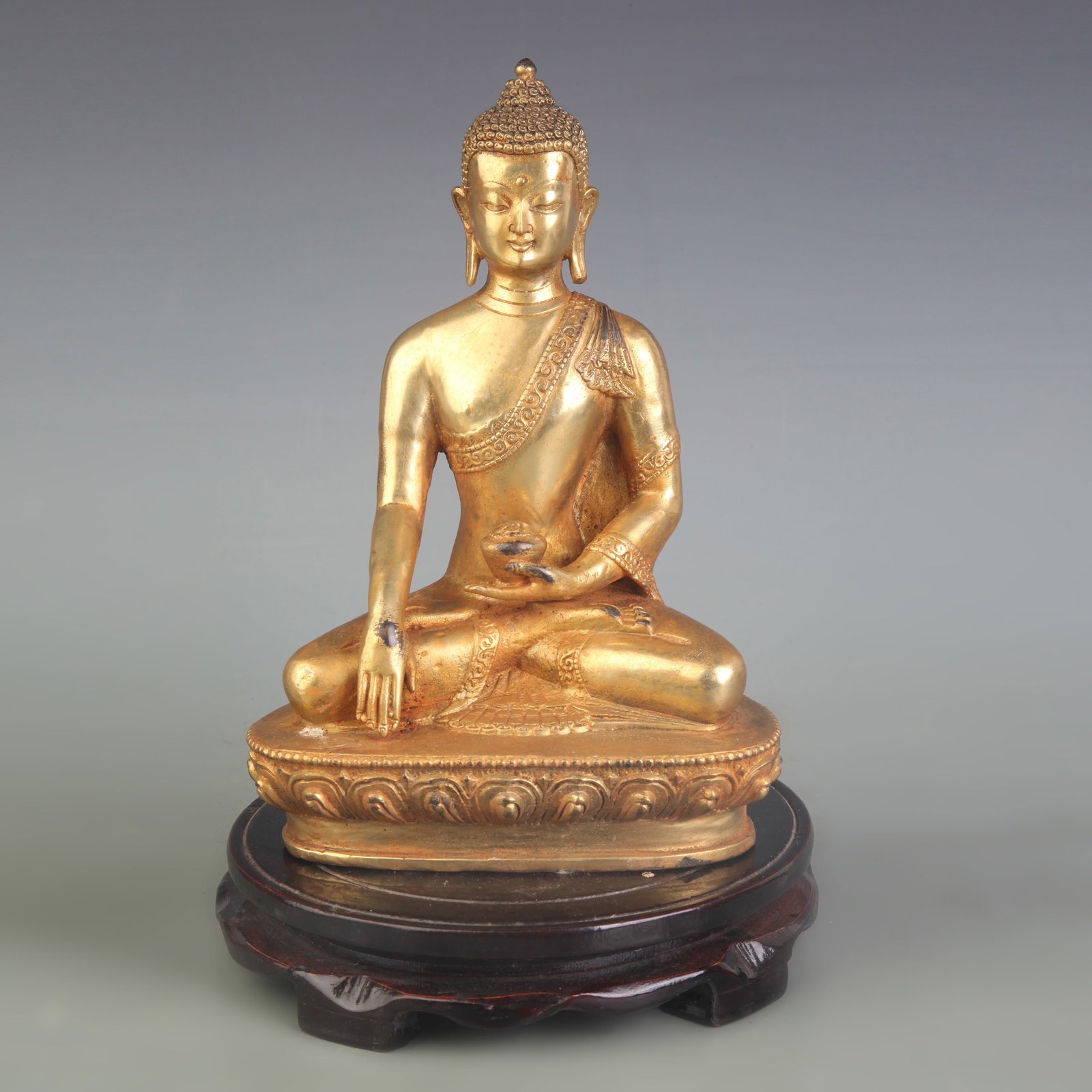A GILT BRONZE FIGURE OF SHAKYAMUNI BUDDHA: Qing Dynasty; Width: 6.0 inch; High: 8.6 inch; Wooden base for picture and display only.