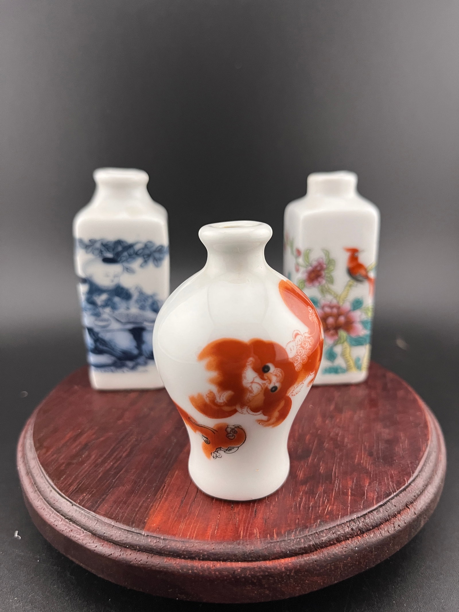 GROUP OF THREE FAMILLE ROSE PORCELAIN SNUFF BOTTLE: Modern; Long: 1.1 inch; Width: 1.1 inch; High: 2.8 inch; Long: 1.1 inch; Width: 1.1 inch; High: 2.8 inch; High: 2.5 inch; Diameter: 1.6 inch. Wooden base for picture and display only.