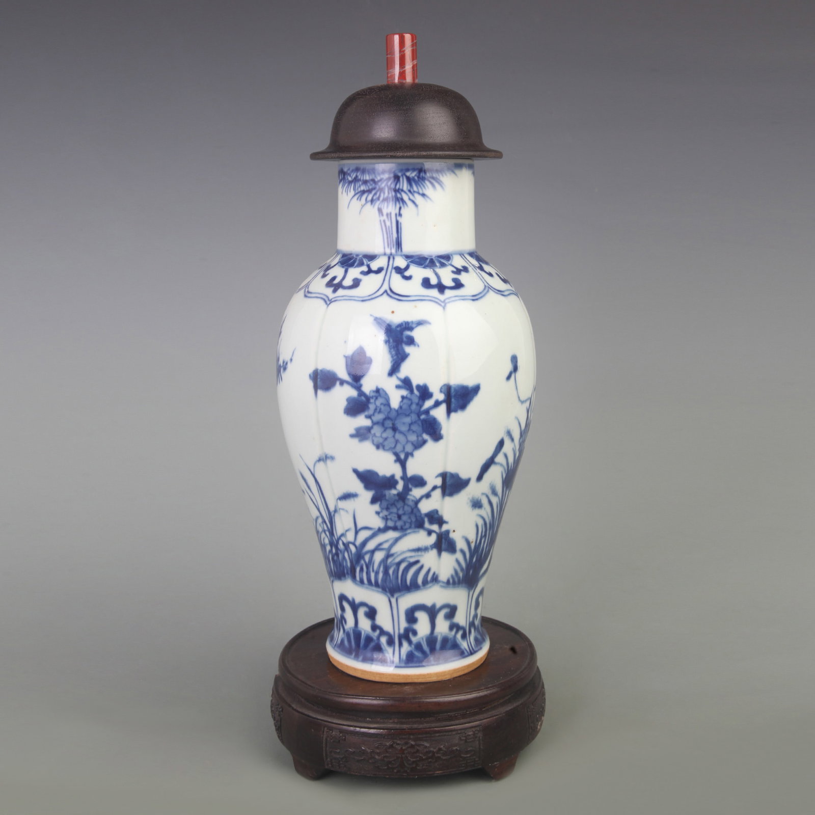 BLUE AND WHITE FLORAL-AND-BIRD GINGER JAR WITH HARDWOOD LID AND JADE FINIAL: Qing Dynasty; Diameter: 4.7 inch; High:12.5 inch. Wooden base for picture and display only.