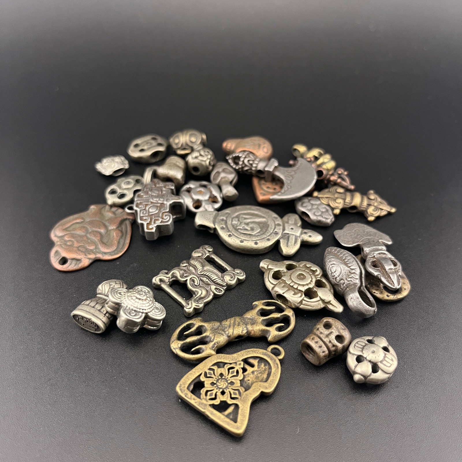 GROUP OF SMALL TIBETAN BUDDHISM RITUAL CHARMS AND BEADS: Modern; Long: 0.62 inch to 1.6 inch; Width: 0.42 inch to 0.8 inch; High: 0.2 inch to 0.13 inch.