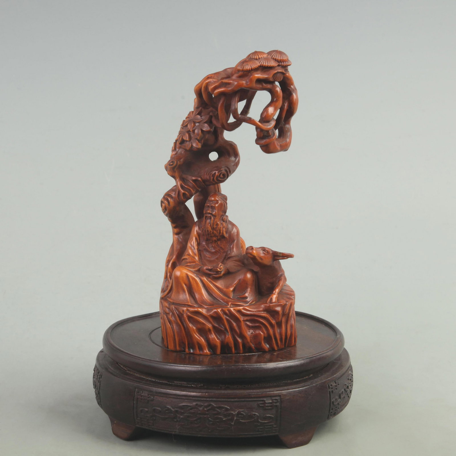 A BOXWOOD CARVING OF FIGURES BENEATH PINE TREES: 20th Century; High: 6 inch; Width: 3.5 inch; Long: 2.8 inch. Wooden base for picture and display only.
