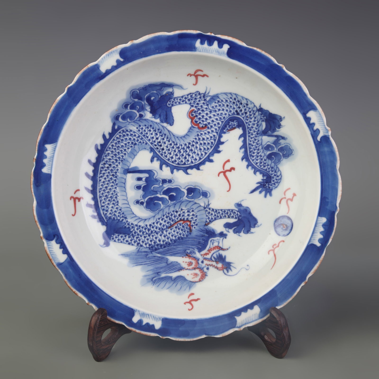 A BLUE AND WHITE AND UNDERGLAZE RED DISH WITH DRAGON MOTIF: Qing Dynasty; Diameter: 8.7 inch; Wooden base for picture and display only.