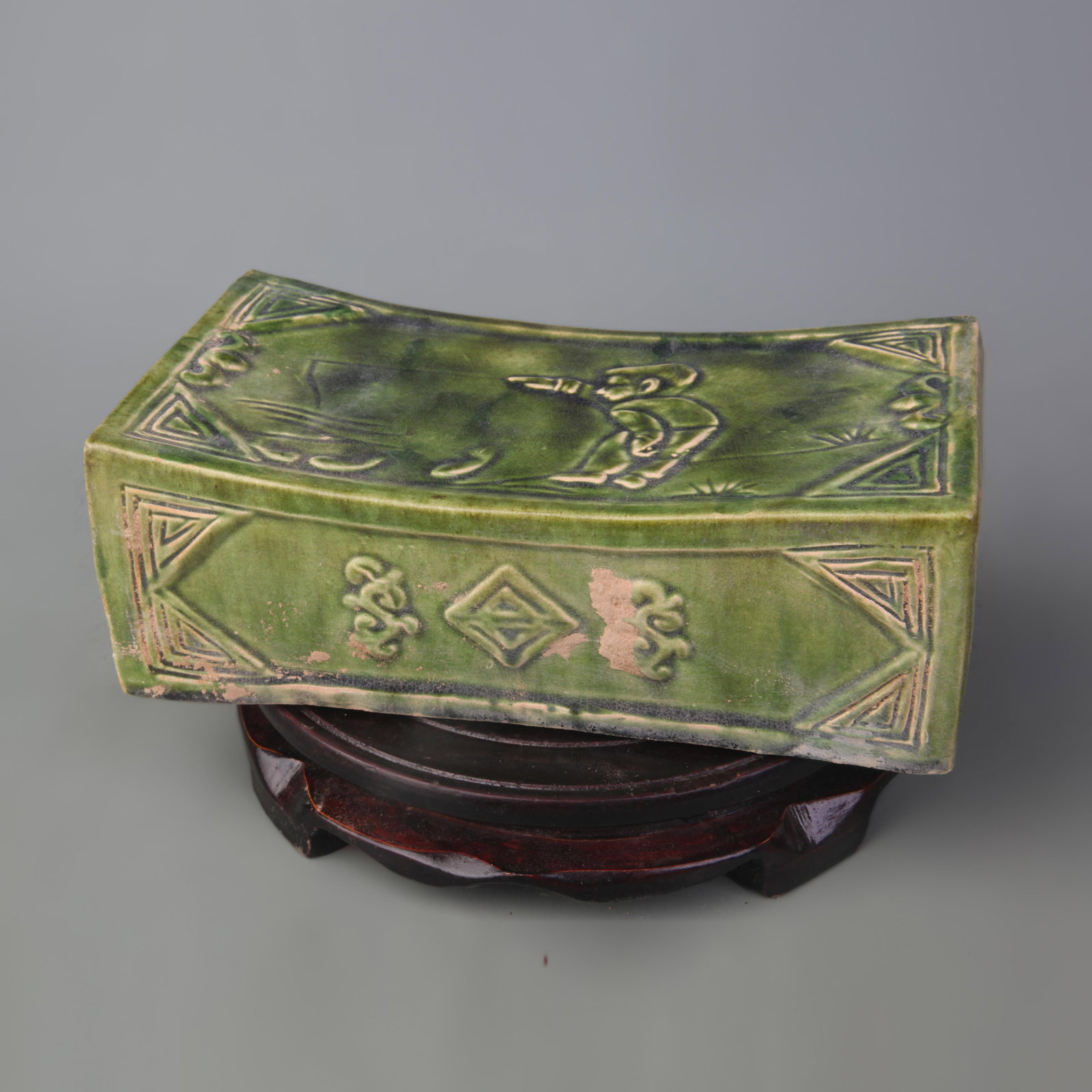 A GREEN-GLAZED PORCELAIN PILLOW: Tang Dynasty Style; Long: 7.4 inch; High: 2.6 inch; Wooden base for picture and display only.