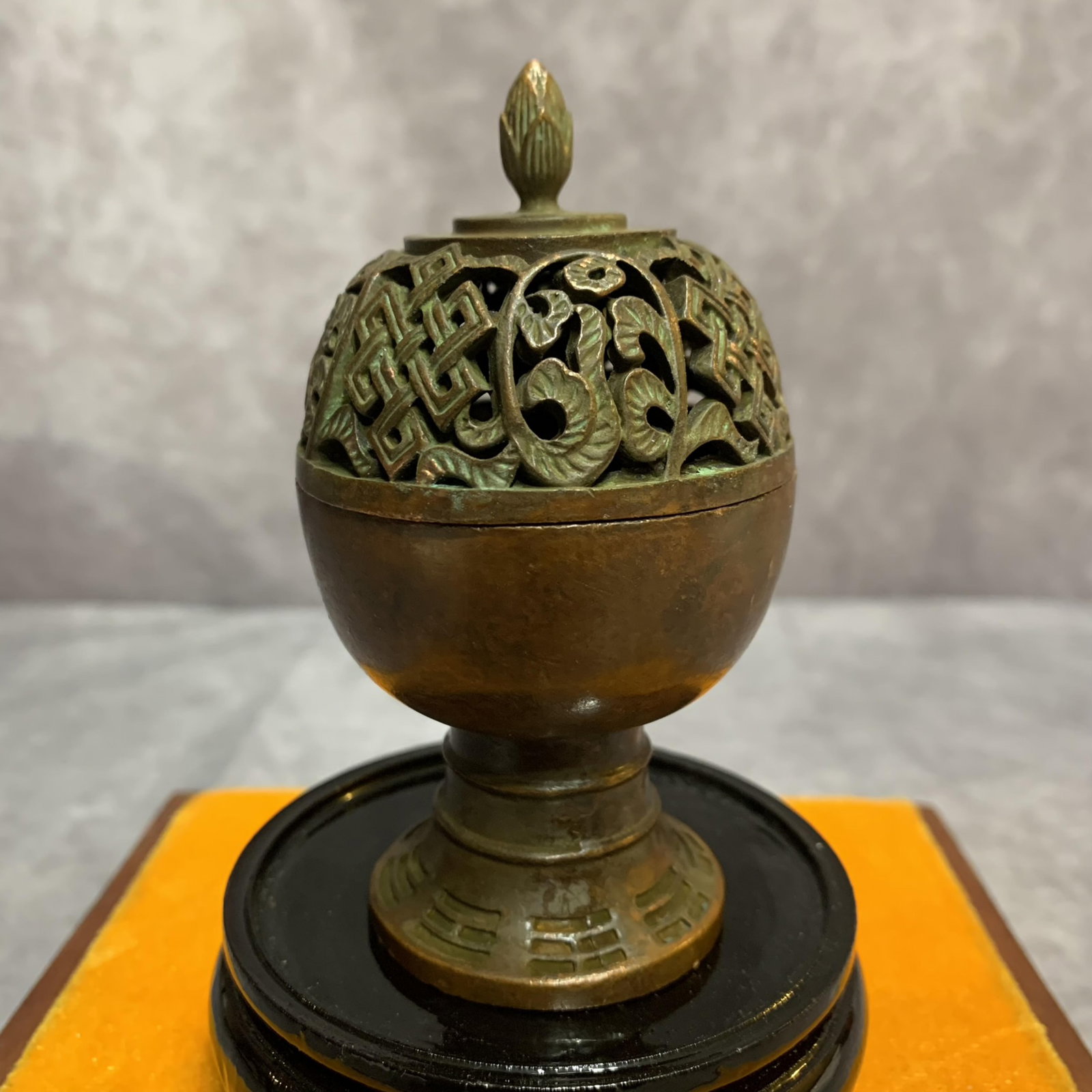 A FINELY CARVED ROUND BRONZE INCENSE BURNER: Modern; High: 3.8 inch; Diameter: 2.1 inch. Wooden base for picture and display only.