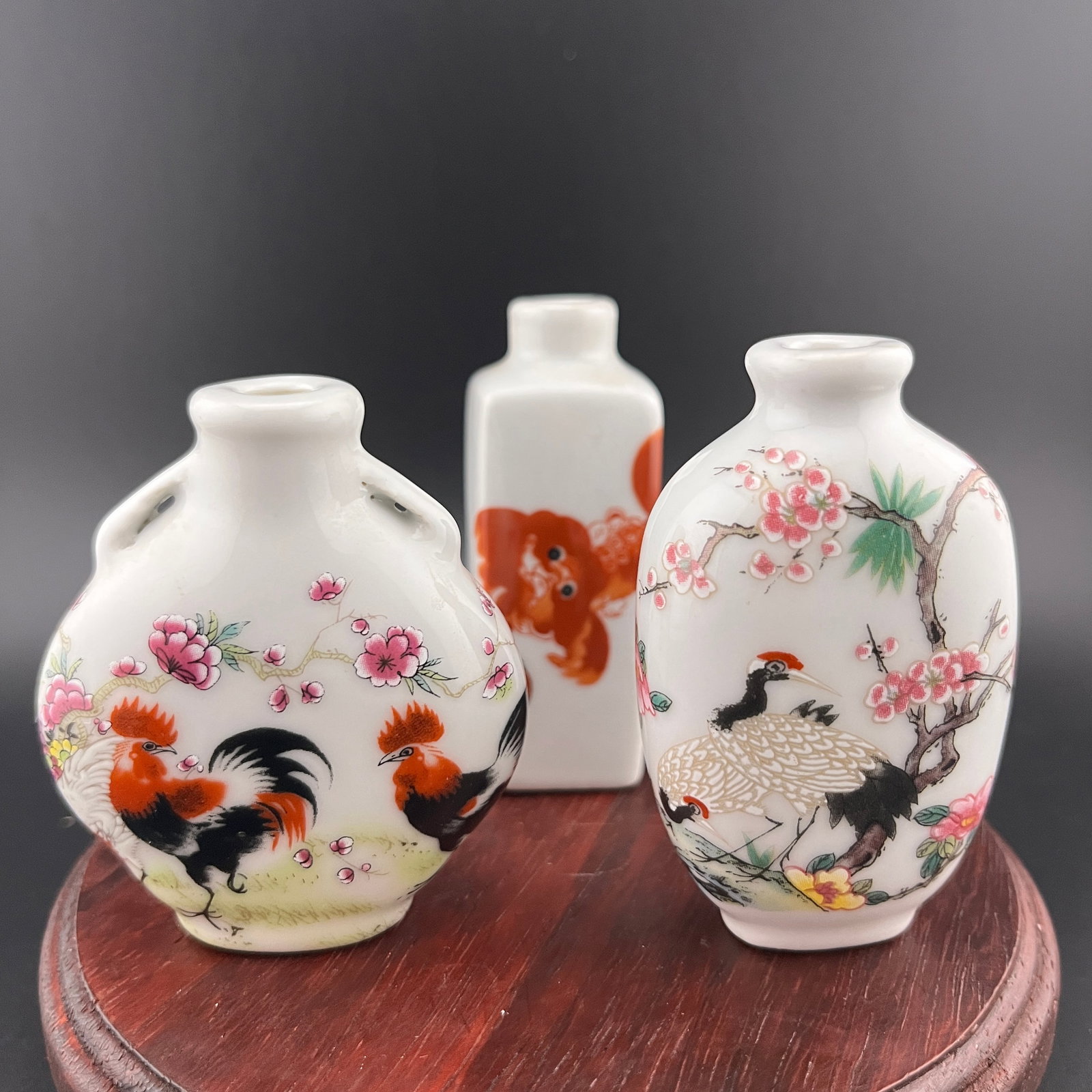 GROUP OF THREE FAMILLE ROSE PORCELAIN SNUFF BOTTLE: Modern; Long: 1.08 inch; Width: 1.08 inch; High: 2.85 inch. Long: 1.7 inch; Width: 1.08 inch; High: 2.76 inch. Long: 2.2 inch; Width: 1 inch; High: 2.6 inch. Wooden base for picture and display only.