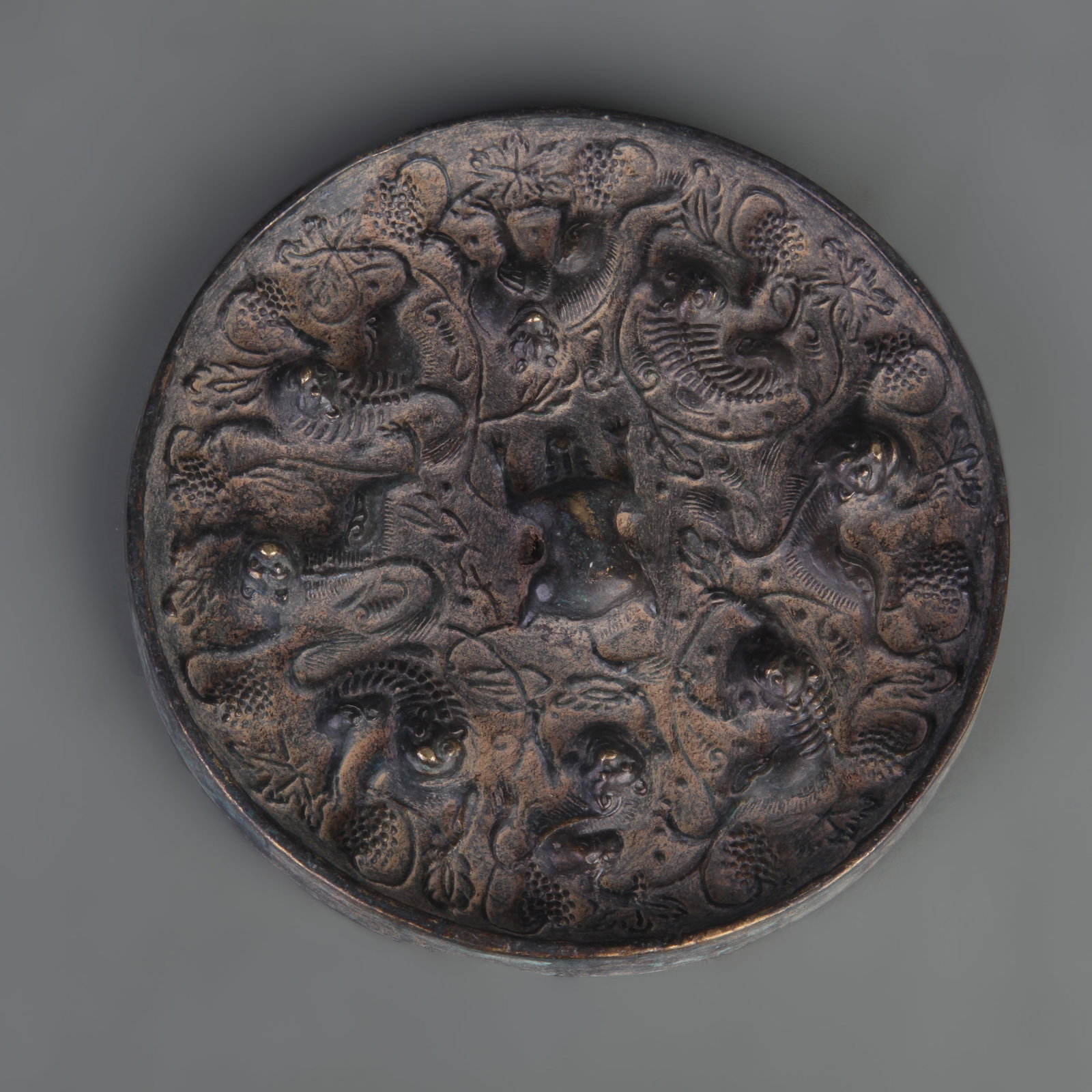 A BRONZE MIRROR CAST WITH AUSPICIOUS BEAST MOTIFS: Tang Dynasty Style; Diameter: 5.3inch; Woodbase for picture and display only