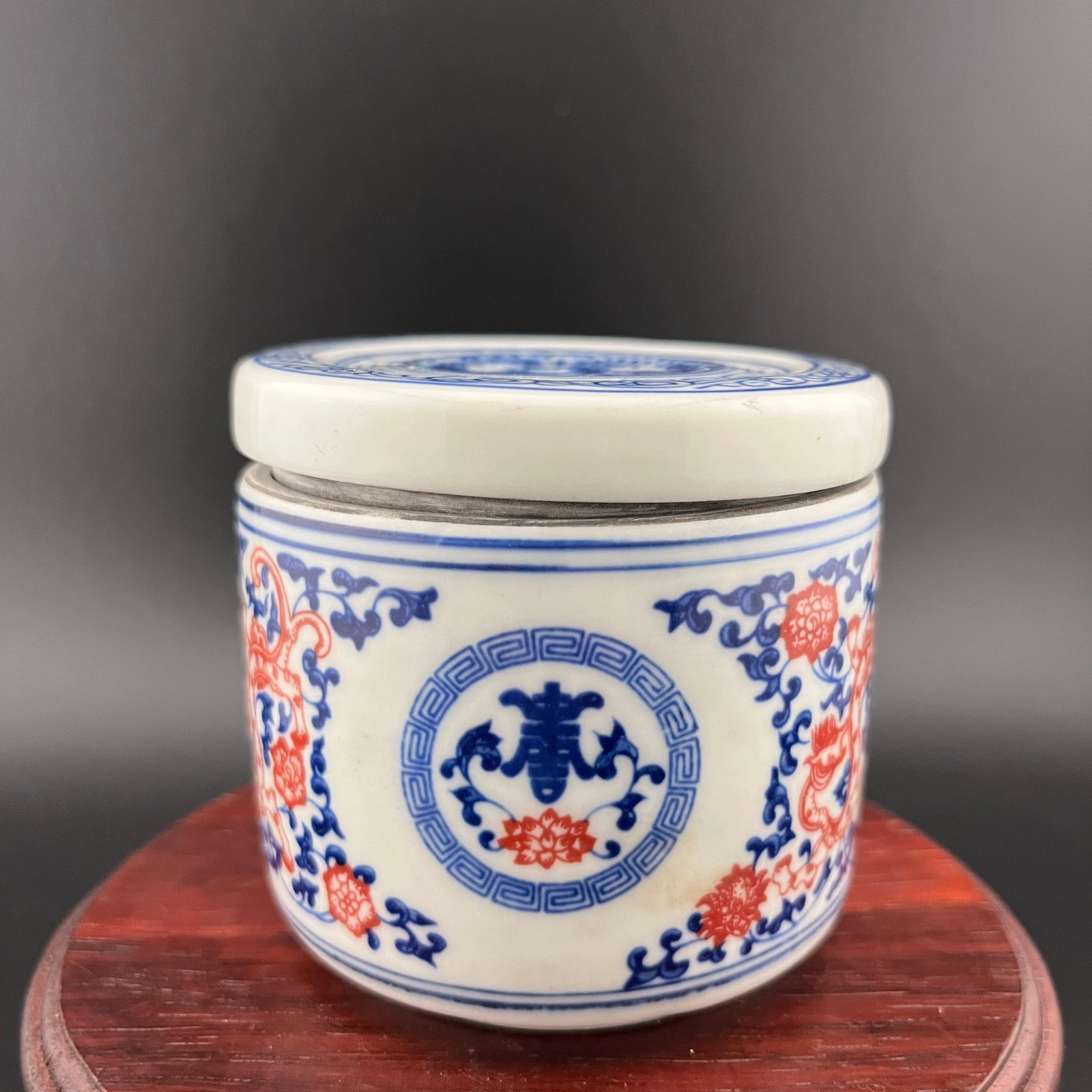 BLUE AND UNDERGLAZE RED (SHOU) PATTERN PORCELAIN LIDDED JAR: 19th Century; High: 2.9 inch; Diameter: 3.1 inch; . Wooden base for display only