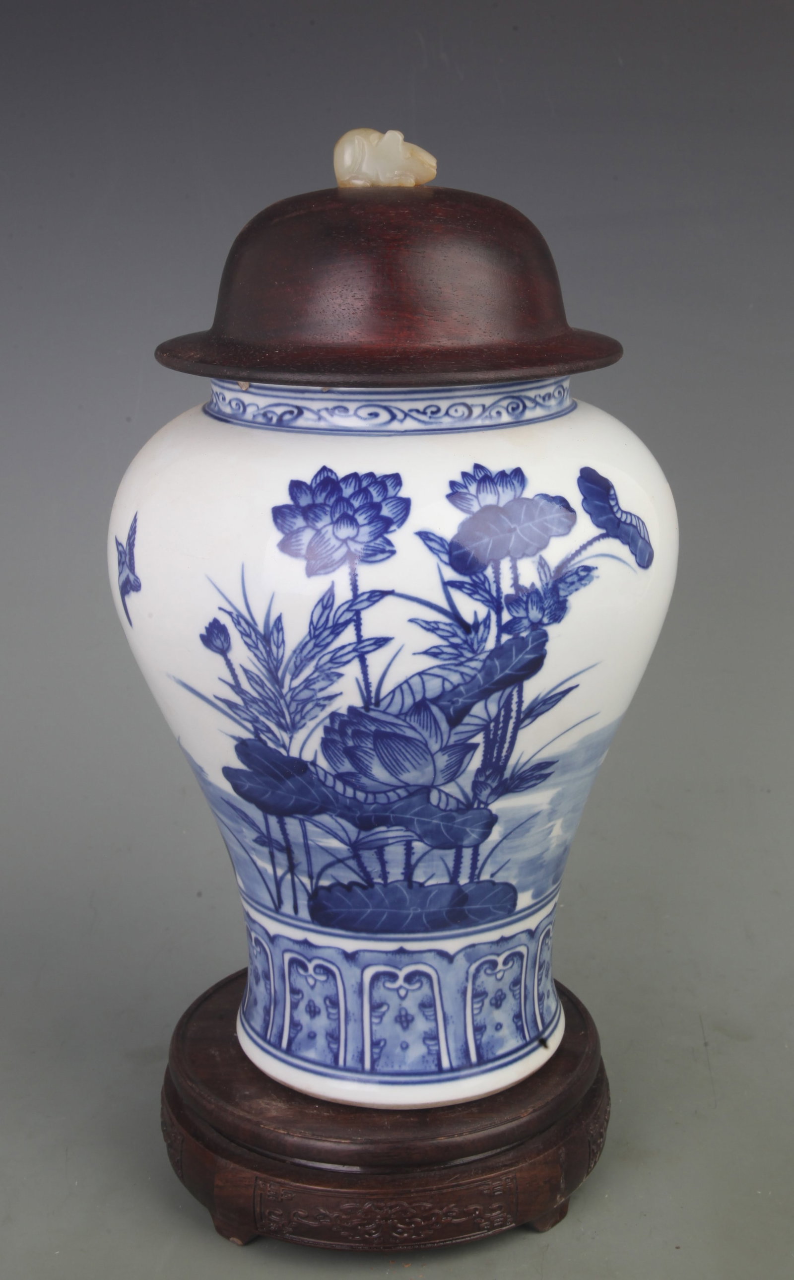 BLUE-AND-WHITE BIRD-AND-FLOWER GINGER JAR (ROSEWOOD LID WITH WHITE JADE FINIAL): Qing Dynasty; D: 7.0inch; High: 13.0inch. Wooden base for display only