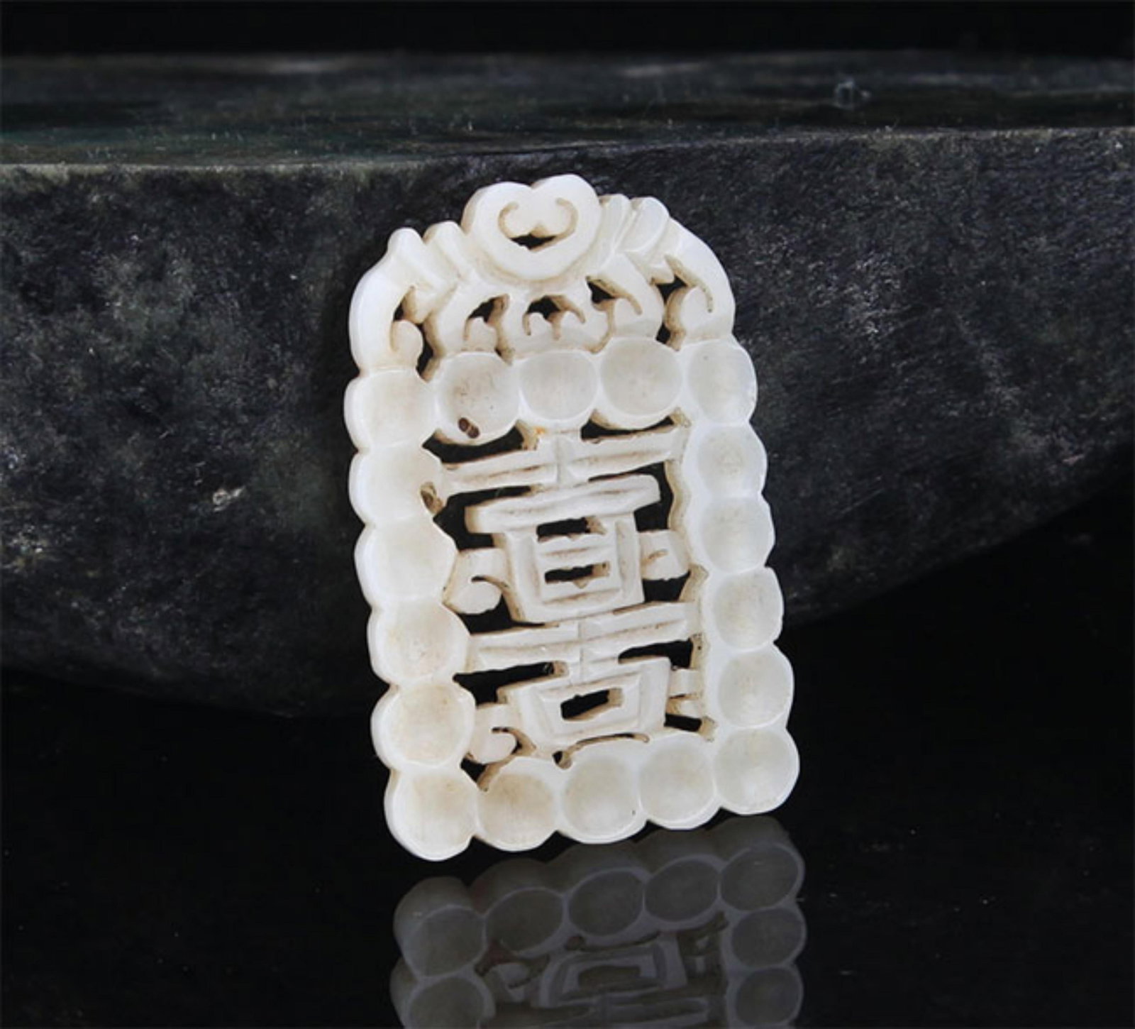 A FINE HE TIAN PALE CELADON JADE PENDANT: Modern; High: 1.75 inch; Width: 1.0 inch; . Wooden base for display only