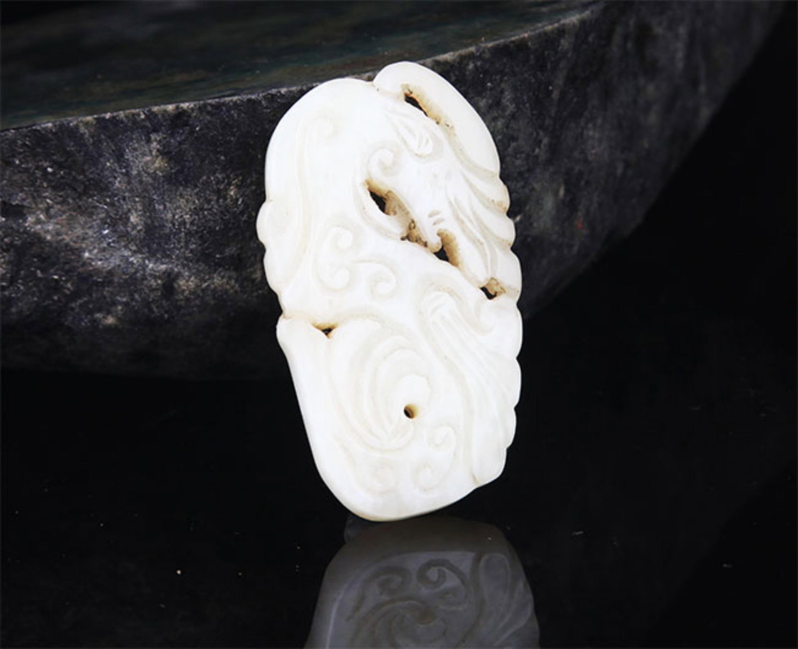 A FINE HETIAN PALE CELADON JADE PENDANT: Modern; High: 2.75 inch; Width: 1.75 inch; . Wooden base for display only