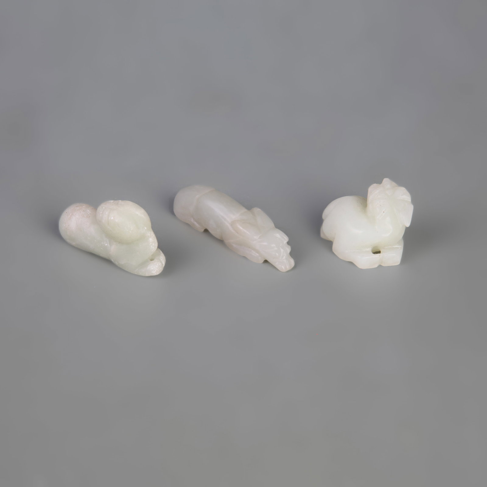 GROUP OF HETIAN JADE PENDANTS: 19th Century; Width: 0.5 inch-1.0 inch; Long: 1.3 inch-2.2 inch; . Wooden base for display only