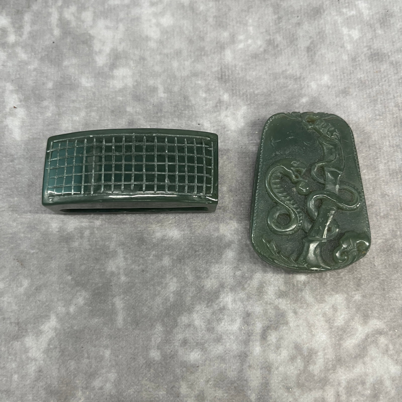 GROUP OF TWO HETIAN GREEN JADE PENDANT: Modern; Long: 1.9 inch; Width: 0.8 inch; High: 0.62 inch; Long: 1.9 inch; Width: 1.3 inch; High: 0.38 inch;. Wooden base for display only