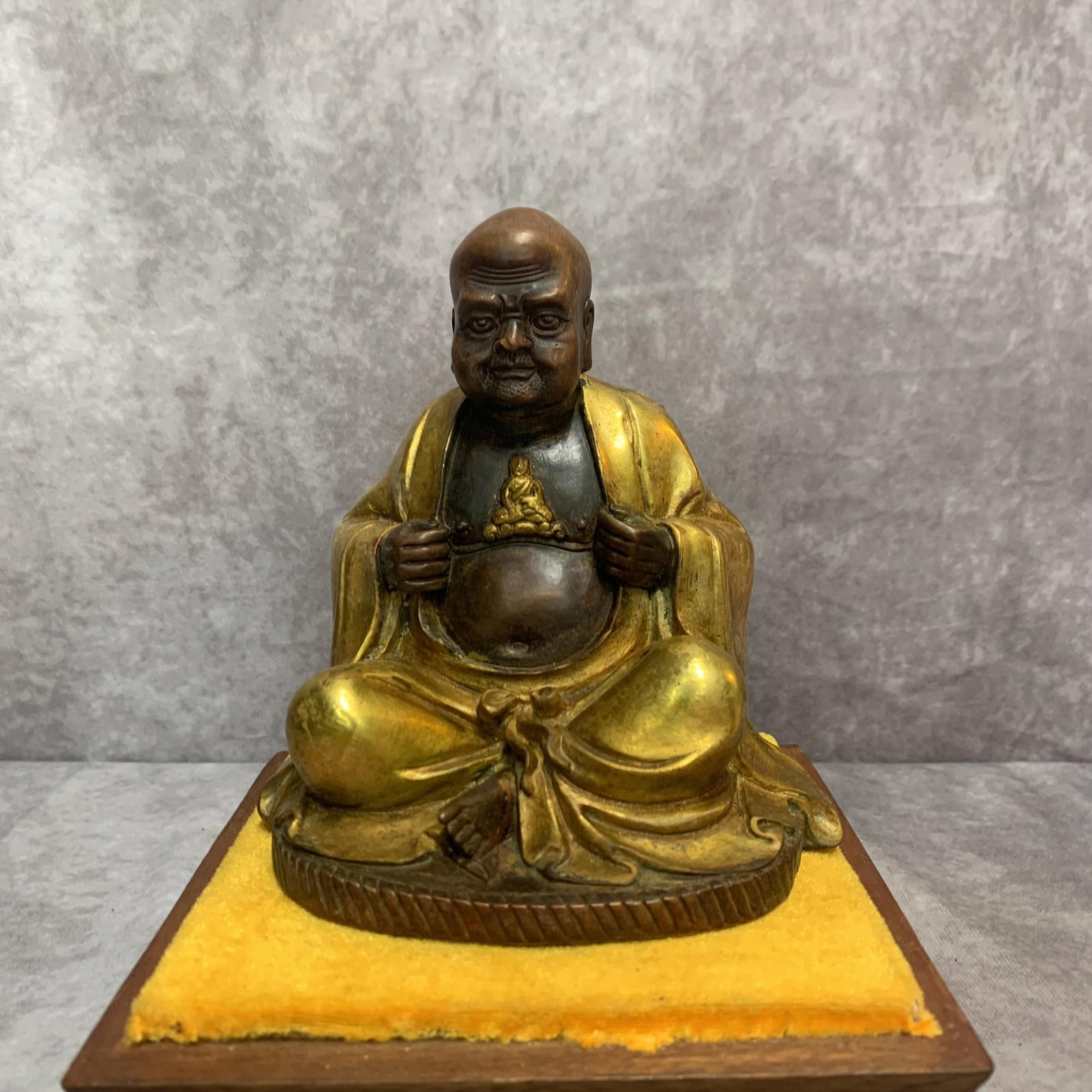 PARTIAL-GILT BRONZE STATUE OF THE ARHAT (LUOHAN) GOBAKA: 20th Century; High: 5.9 inch; Width: 5.4 inch; Long: 4.0 inch. Wooden base for display only
