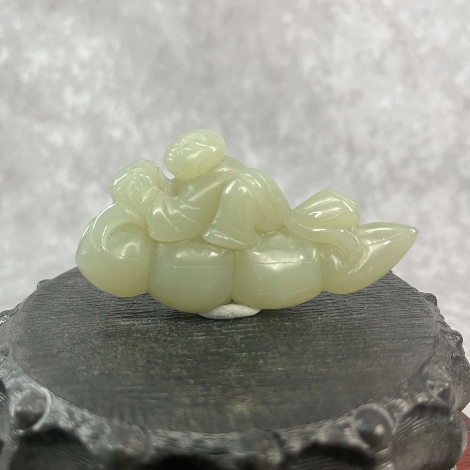 A FINE HETIAN JADE IN FIGURE OF BOY RIDING A DOUBLE GOURD: Qing Dynasty; Long: 2.98 inch; Width: 1.54 inch; High: 0.6 inch; ;Wooden base for picture and display only.