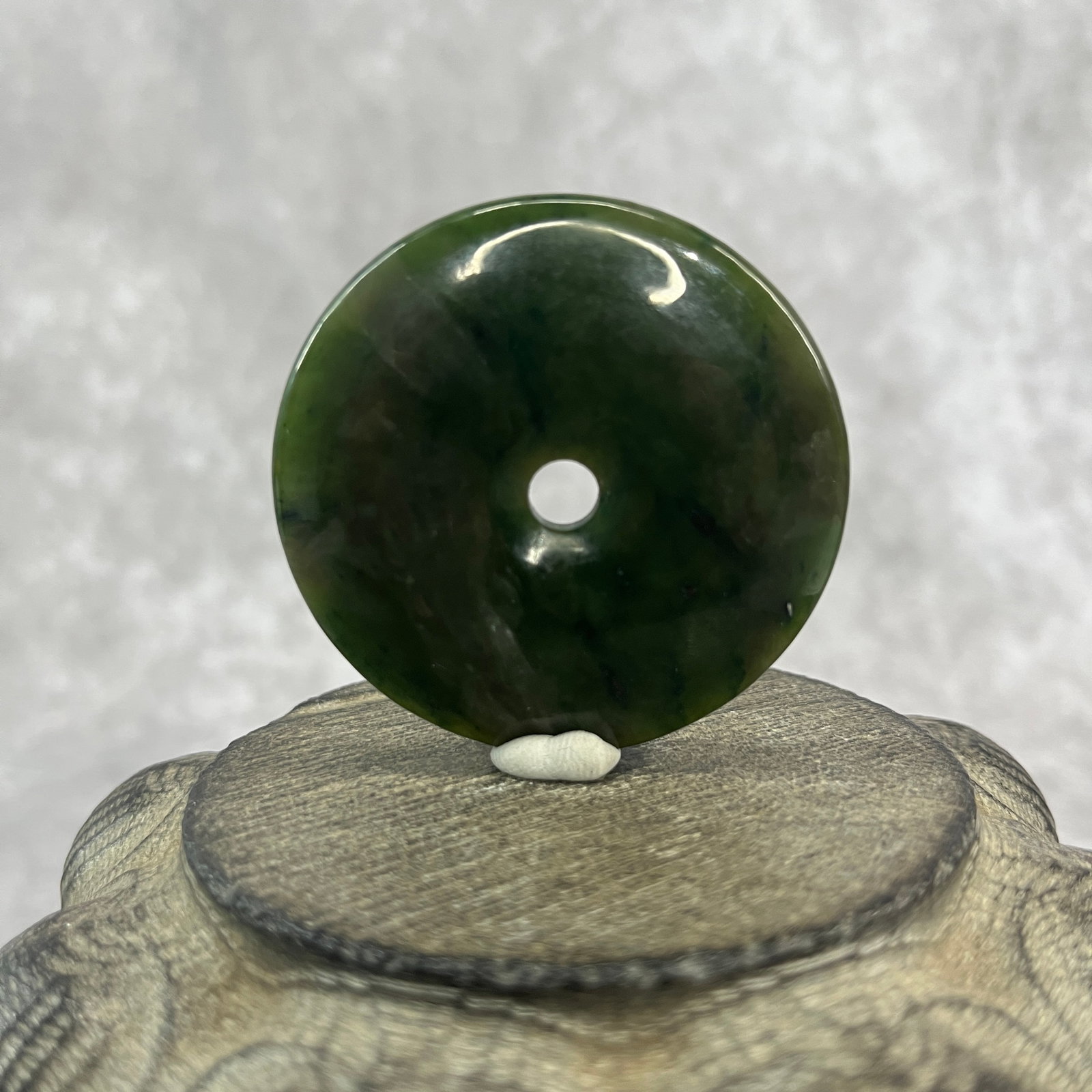 A FINE DARK GREEN JADE BI PENDANT: Modern; High: 0.3 inch; Diameter: 2.02 inch; ;Wooden base for picture and display only.