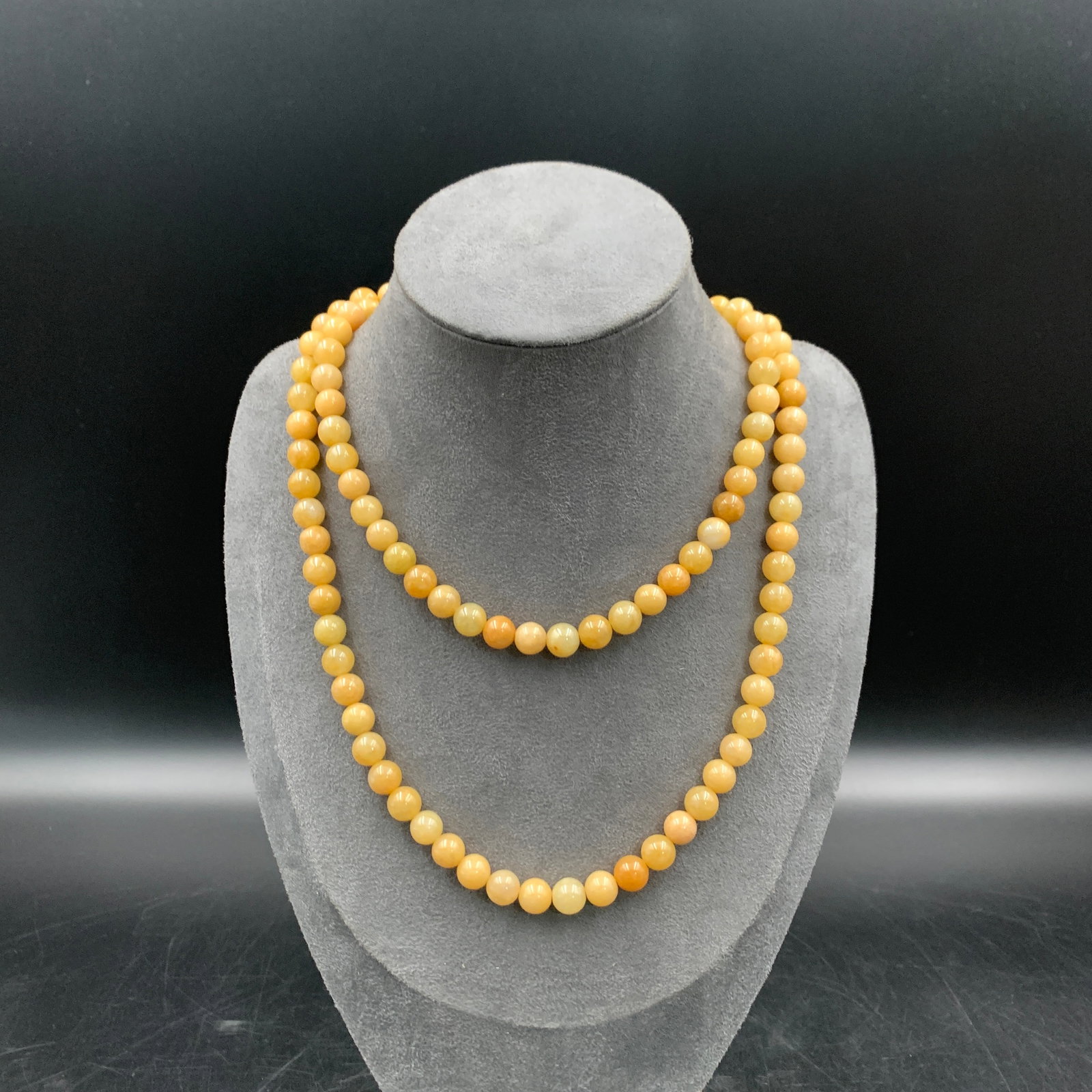 A FINE YELLOW JADE BEAD NECKLACE: Modern; Long: 17.5 inch; Diameter: 0.3 inch; ;Wooden base for picture and display only.