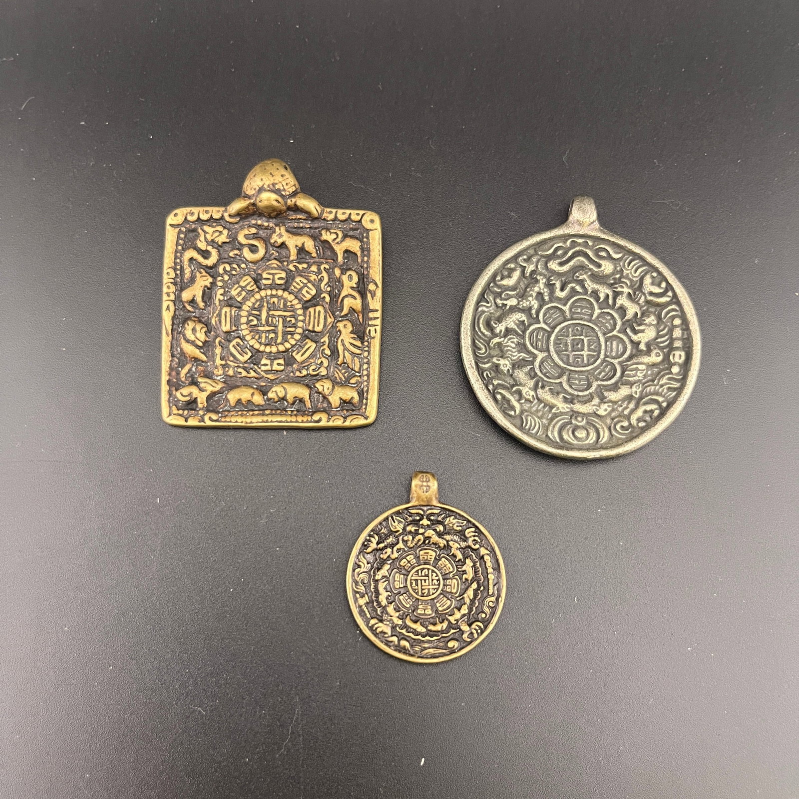 GROUP OF THREE STAMPED METAL PROTECTIVE MELONG PLATES: Republic Period; Long: 2.1 inch; Width: 1.68 inch; High: 0.5 inch; Long: 2.1 inch; Width: 1.8 inch; High: 0.2 inch; Long: 1.32 inch; Width: 1.1 inch; High: 0.12 inch; ;Wooden base for picture and