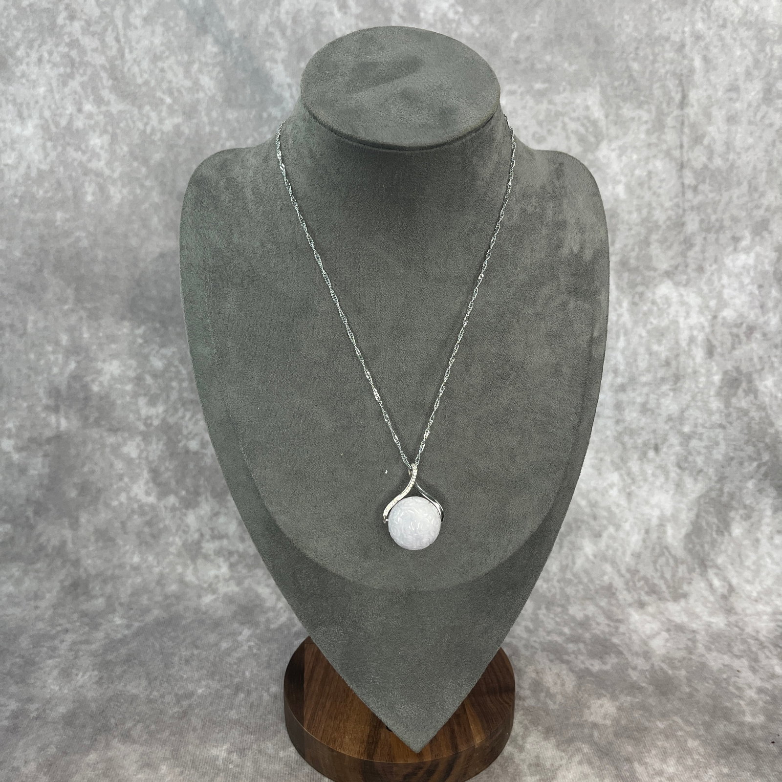 CHINESE CARVED WHITE JADEITE 'CLOUD-SCROLL' SPHERE PENDANT: Modern; Long: 9 inch; Diameter: 0.8 inch; ;Wooden base for picture and display only.