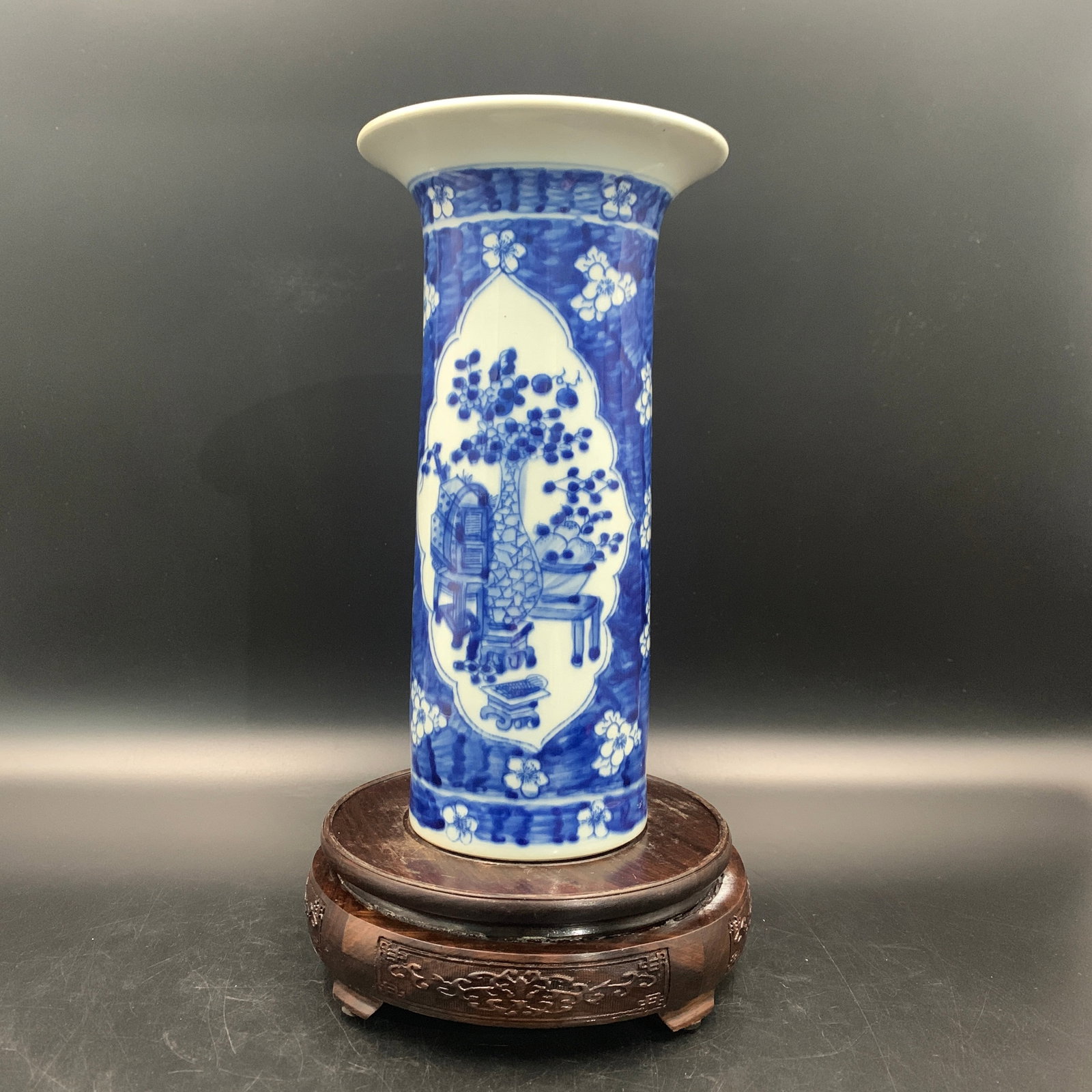 BLUE AND WHITE PORCELAIN CYLINDRICAL GU-FORM VASE WITH SCHOLARS' OBJECTS: Qing Dynasty; High: 9.7 inch; Diameter: 5.2 inch; ;Wooden base for picture and display only.