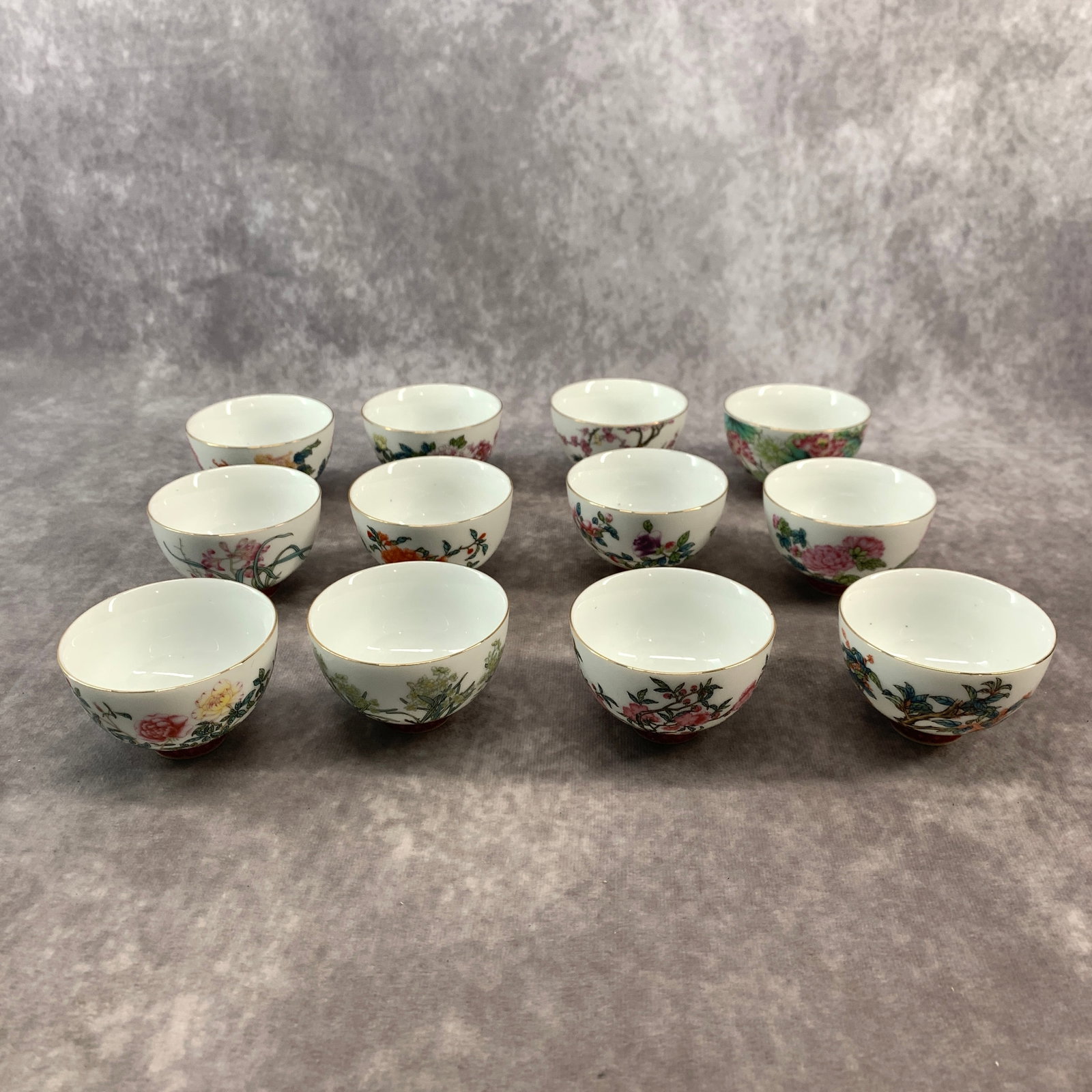 SET OF 12 FAMILLE ROSE FLORAL TEA CUPS: 19th Century; Long: 2.7 inch; Width: 2.7 inch; High: 1.7 inch; . Wooden base for display only