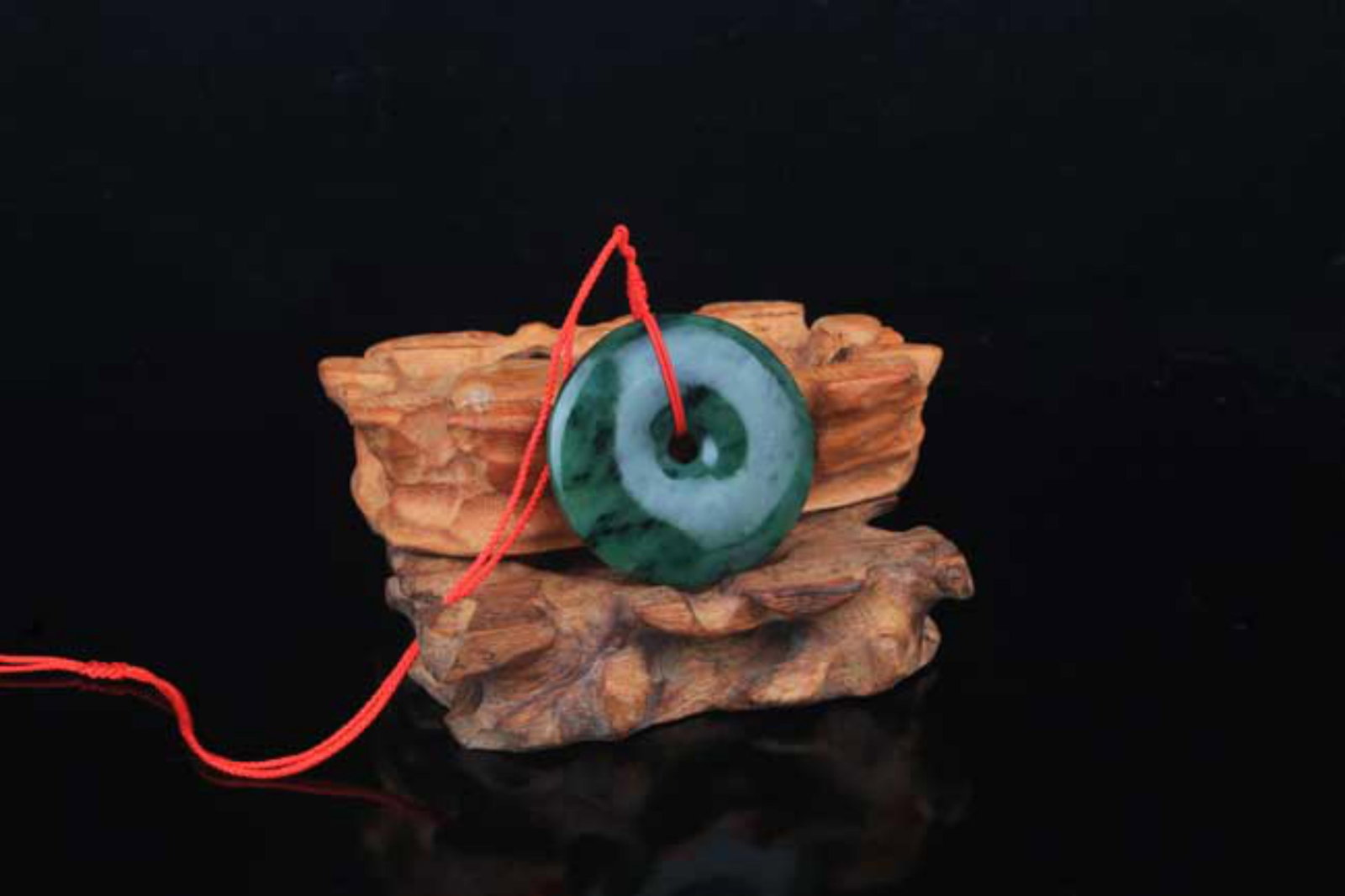 A FINE ROUND GREEN JADE PENDANT: Contemporary; Diameter: 2.0 inch; . Wooden base for display only