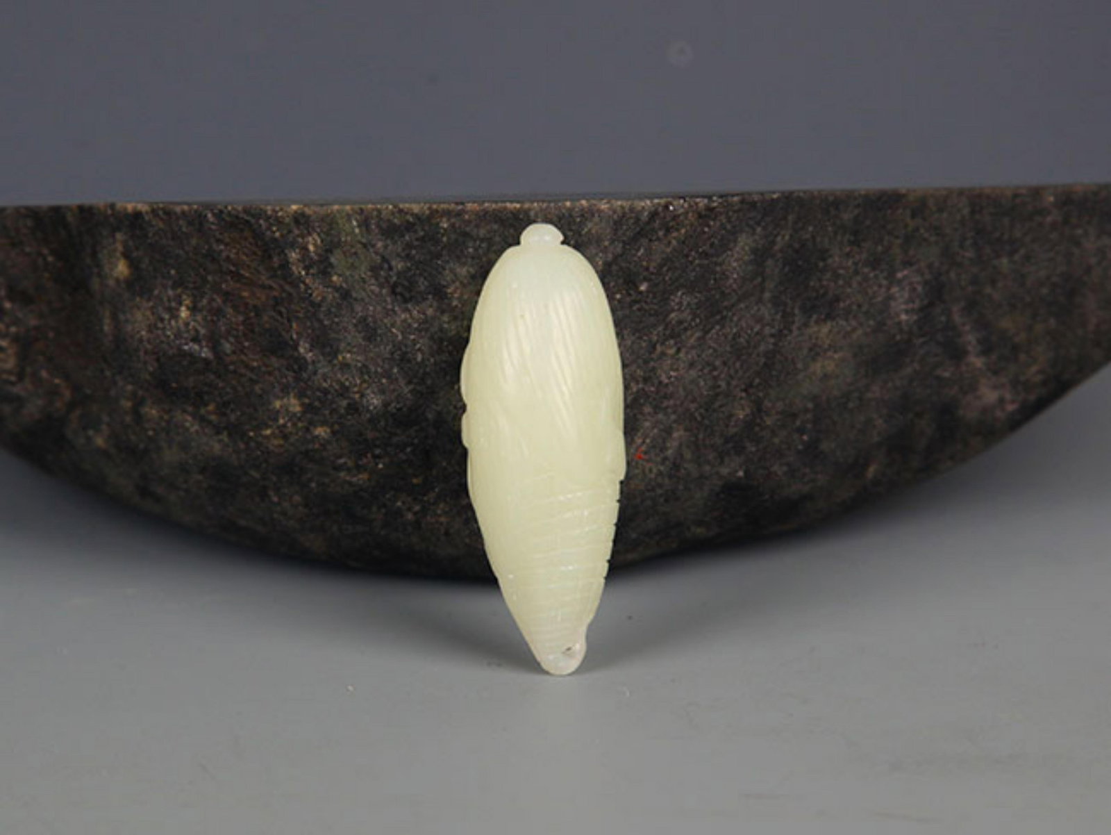 A FINE CORN SHAPED PALE CELADON JADE PENDANT: Modern; High: 1.8 inch . Wooden base for display only