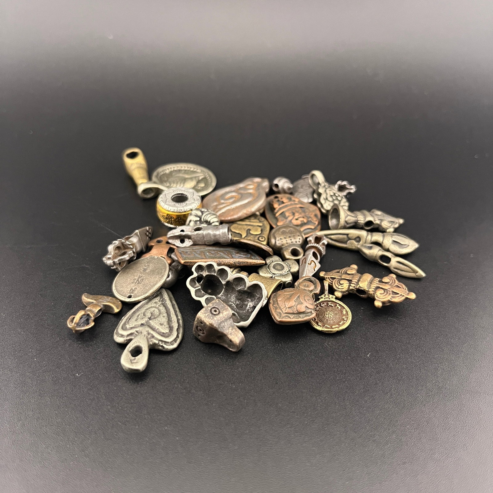 GROUP OF SMALL TIBETIAN AMULETS AND BEADS: Long: 1.18 inch; Width: 0.88 inch; High: 0.18 inch; Long: 0.5 inch; Width: 0.26 inch; . Wooden base for display only